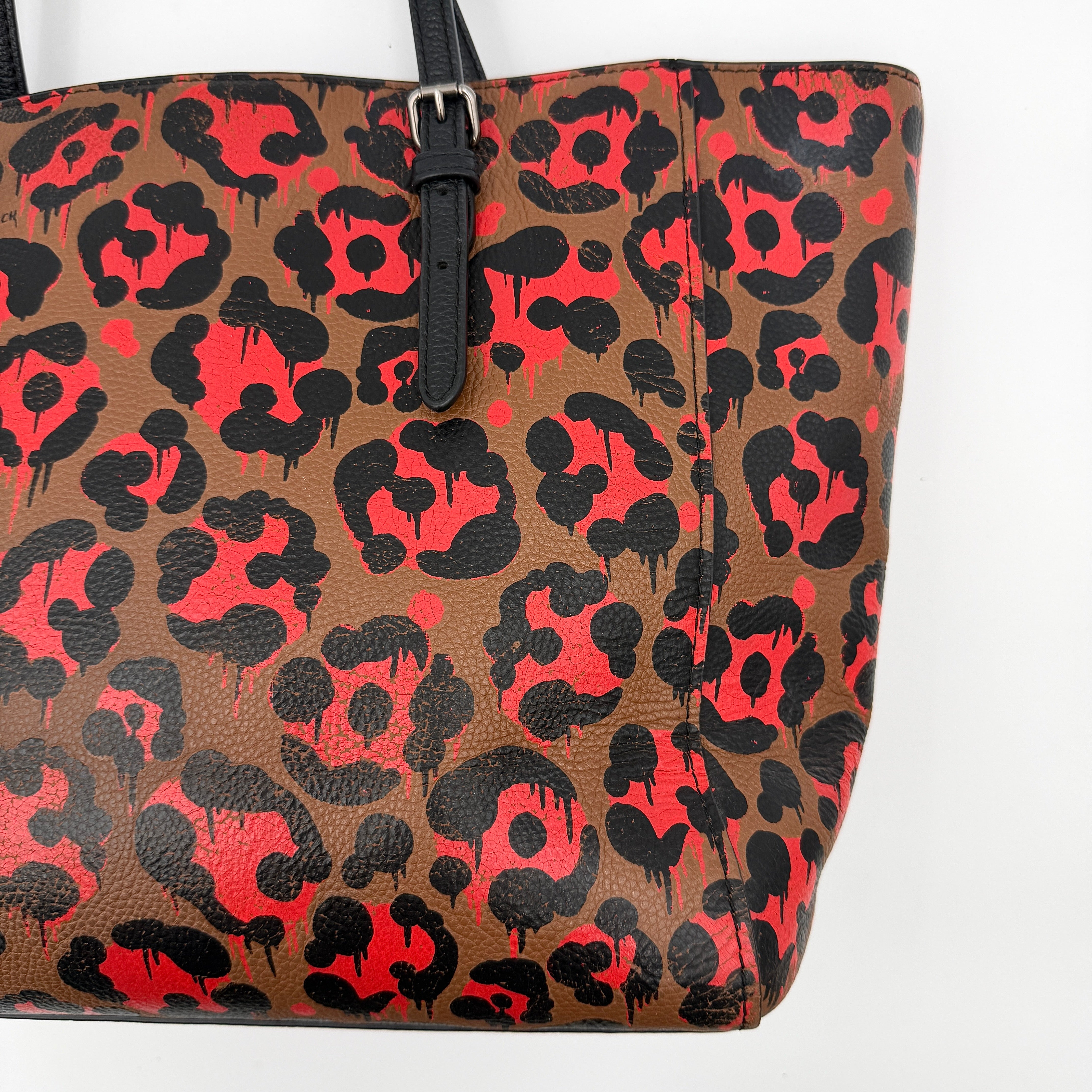 Coach City Tote in brown coated canvas, drenched in a vivid red and black leopard print, with black leather handles and silver hardware details.