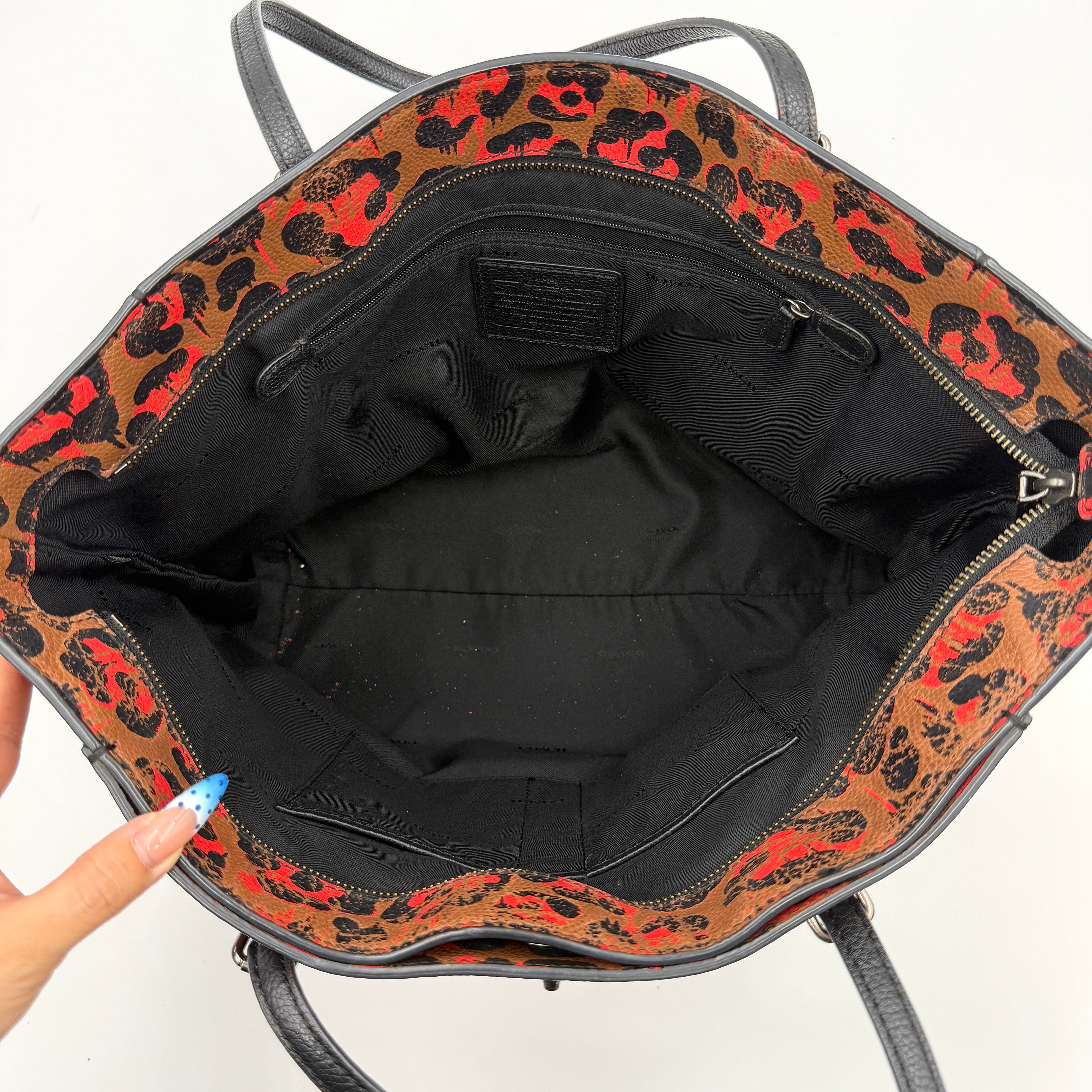 Coach City Tote in brown coated canvas, drenched in a vivid red and black leopard print, with black leather handles and silver hardware details.