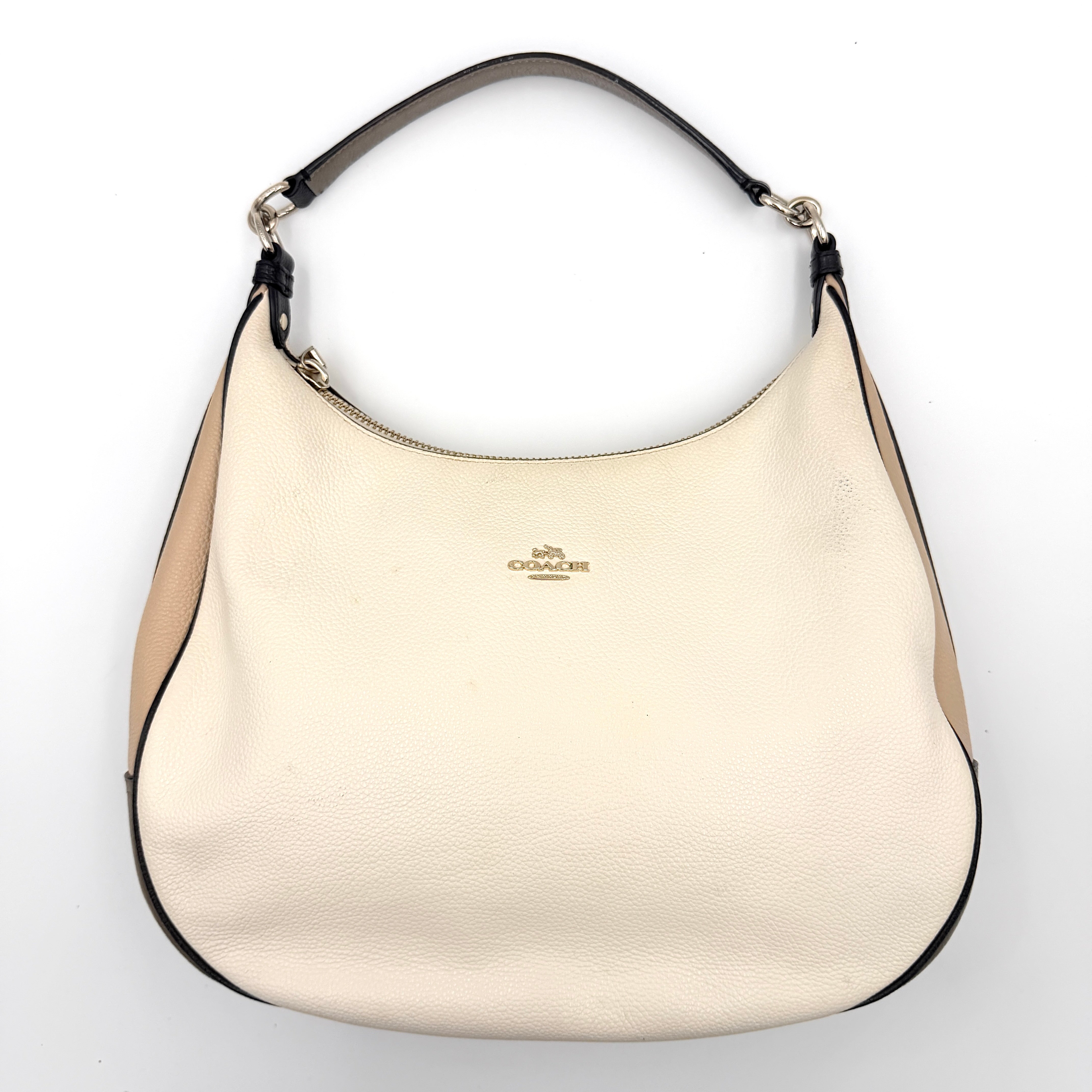 Coach Harley East West Hobo in cream and beige pebbled leather with a sculpted silhouette, black piping, and silver hardware.