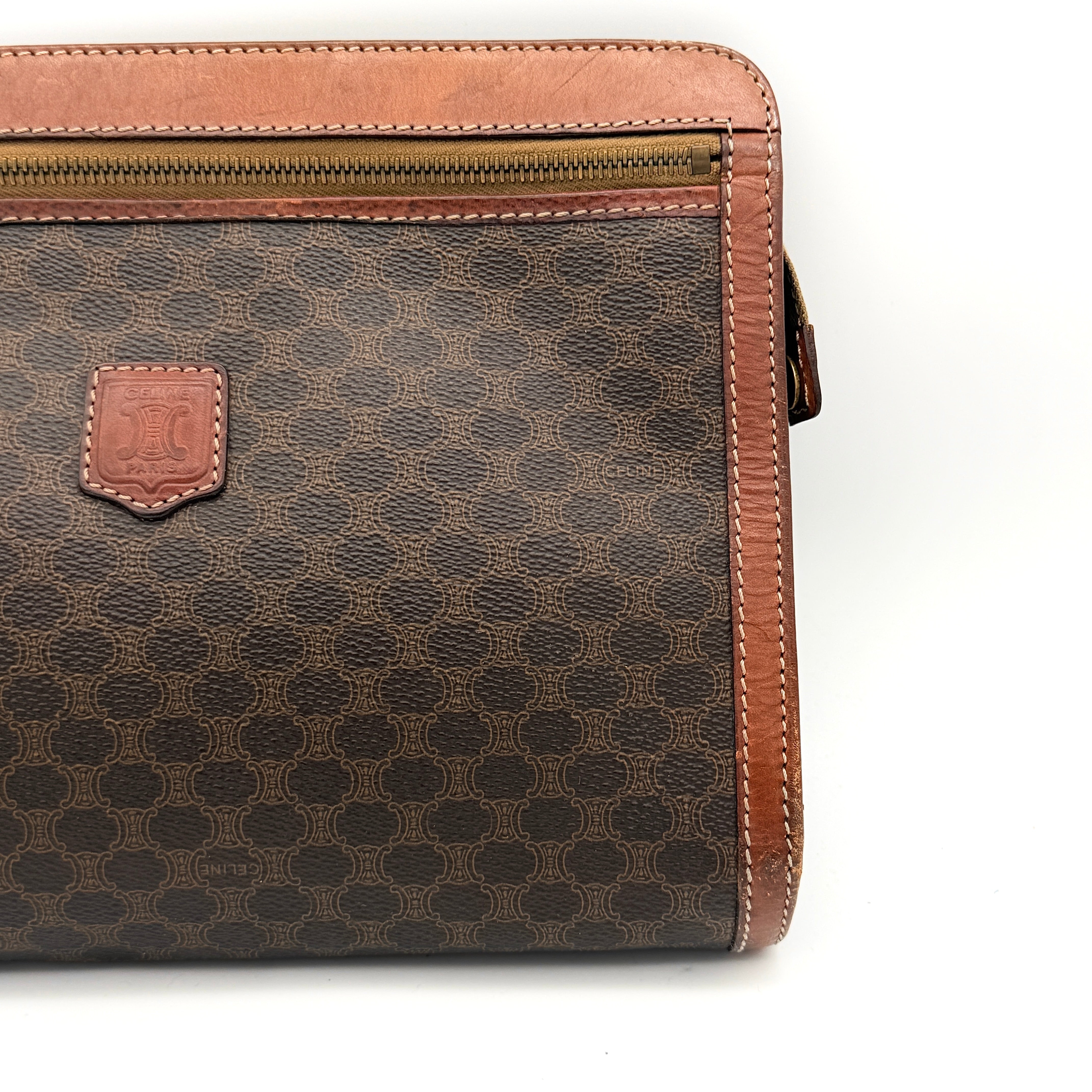 Front view of the Celine Triomphe Macadam clutch bag in brown canvas with tan leather trim and zip pocket.