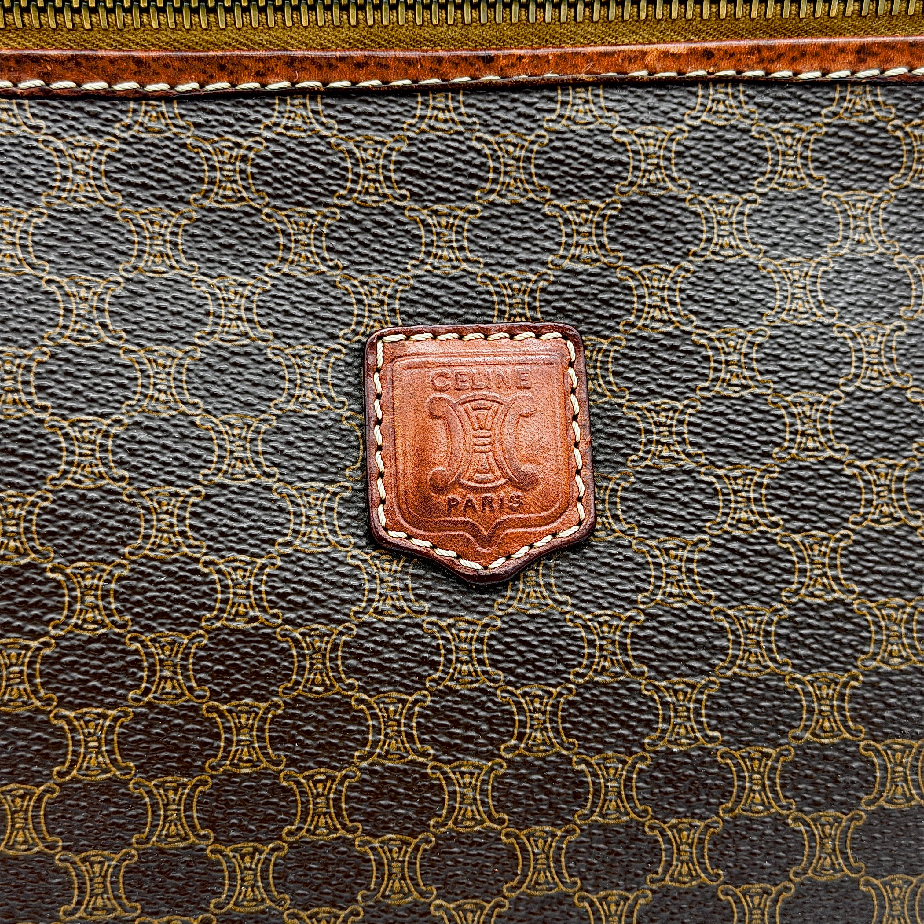 Front view of the Celine Triomphe Macadam clutch bag in brown canvas with tan leather trim and zip pocket.