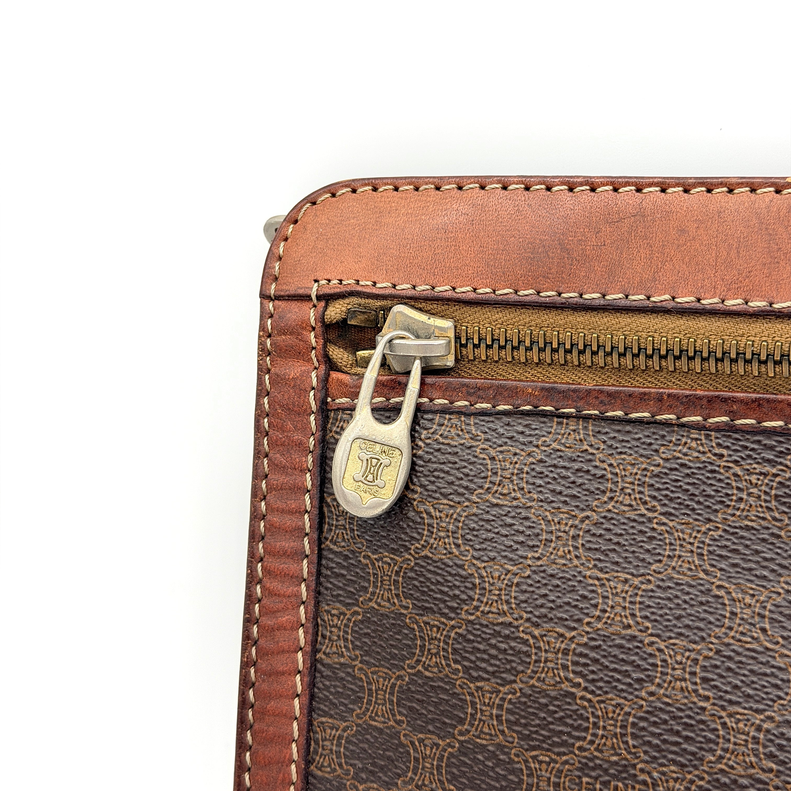 Front view of the Celine Triomphe Macadam clutch bag in brown canvas with tan leather trim and zip pocket.