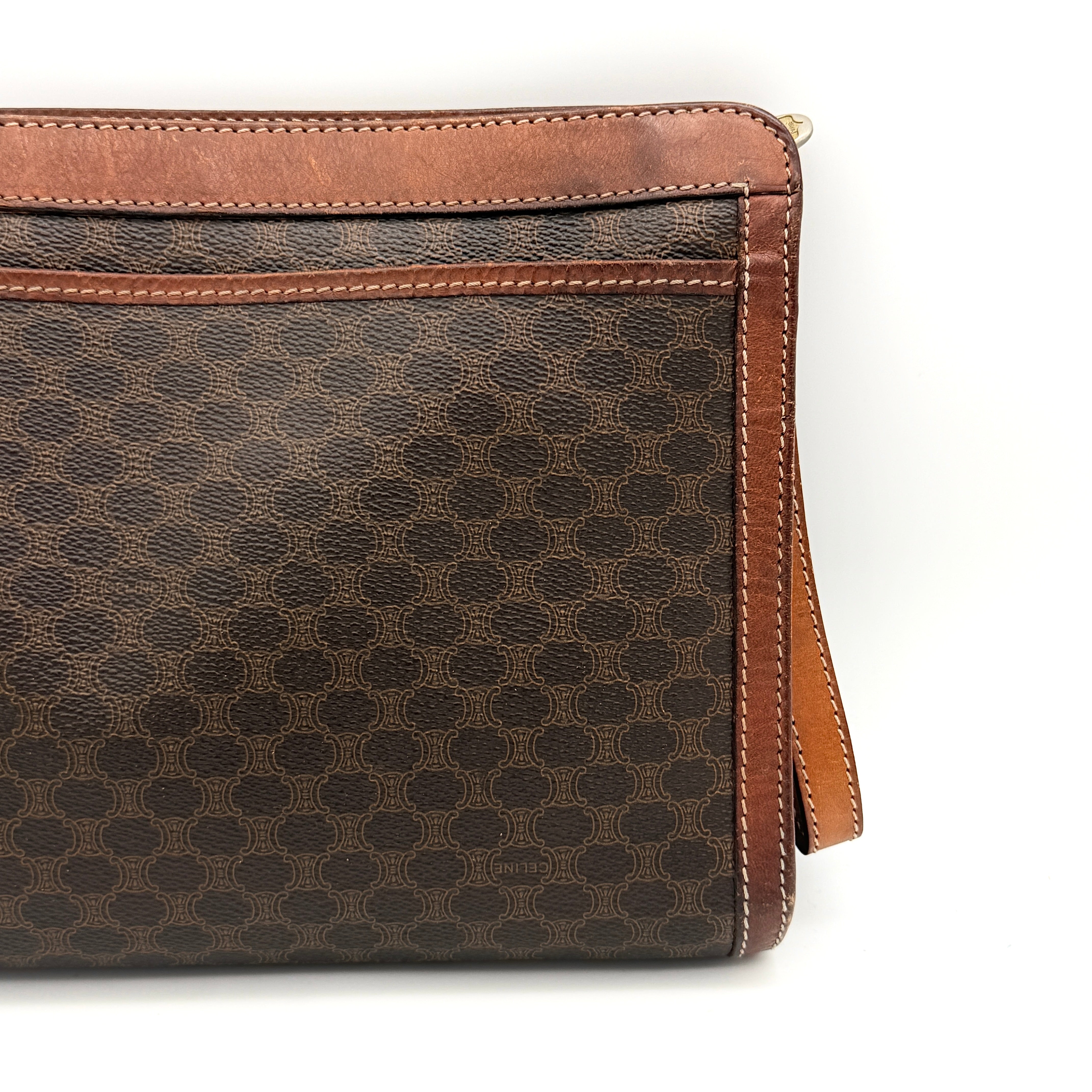 Front view of the Celine Triomphe Macadam clutch bag in brown canvas with tan leather trim and zip pocket.