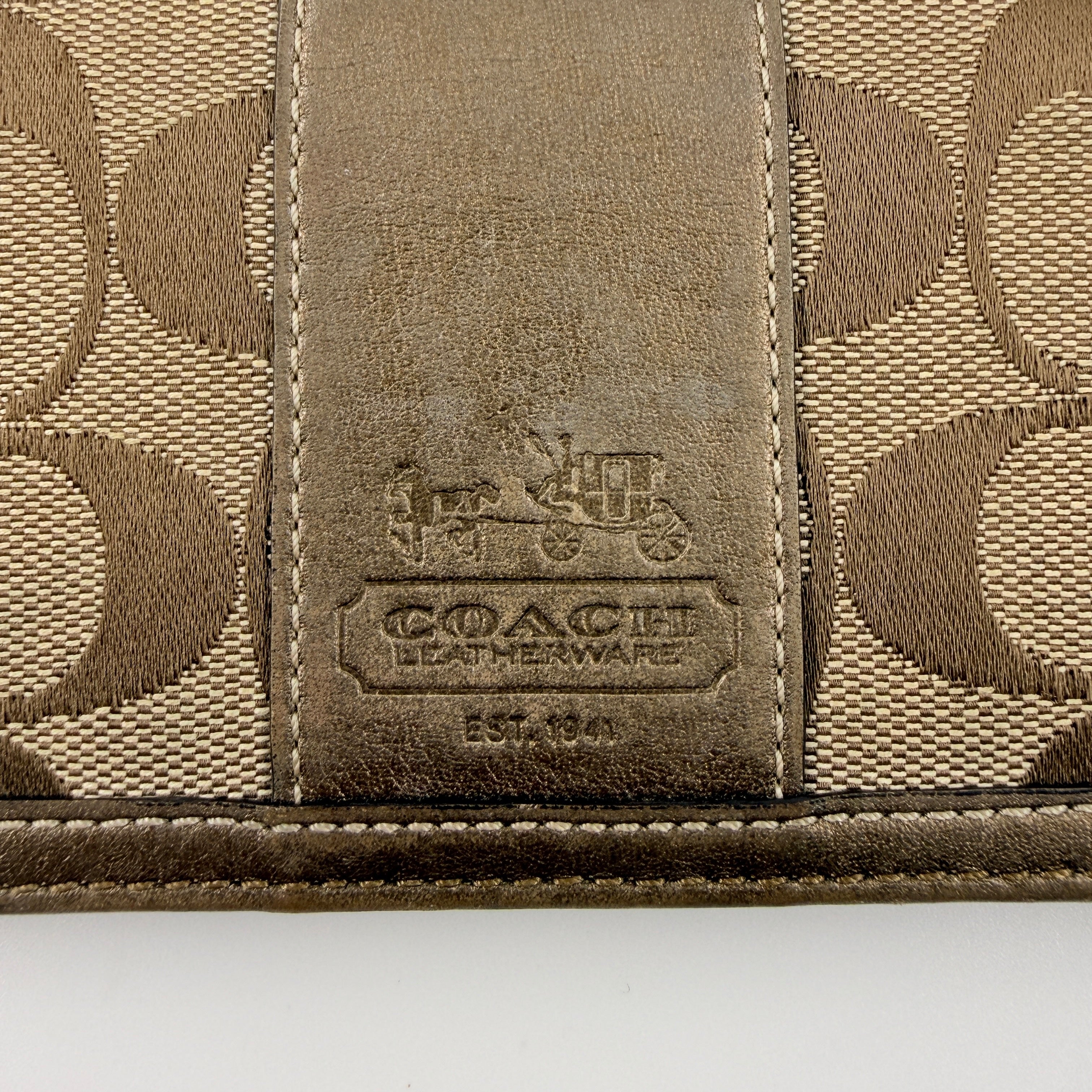 Coach Signature Stripe Snap Wallet in brown jacquard canvas with leather trim and embossed logo, shown against a white background.