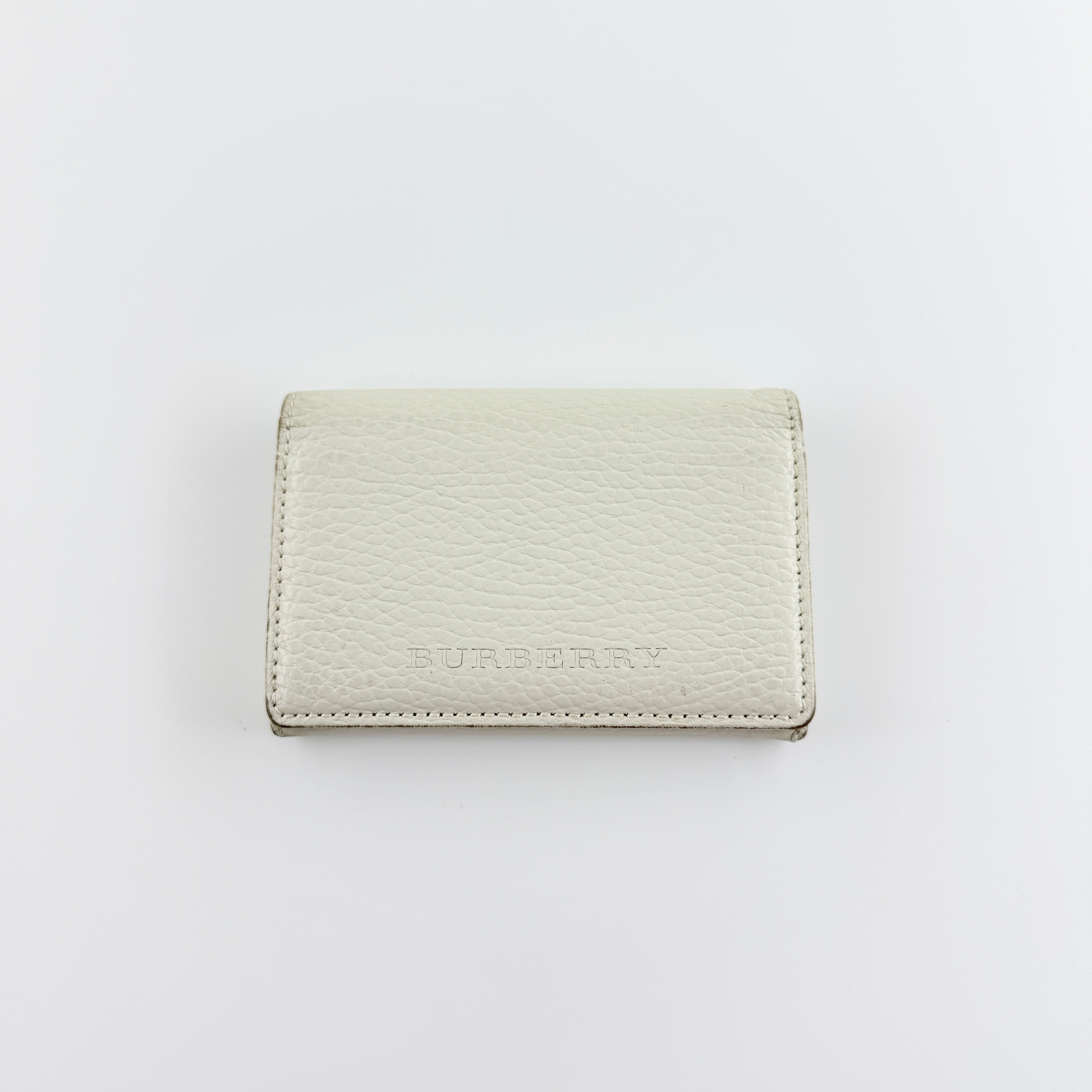 Burberry Nova Check card holder in ivory grained leather with subtle embossed logo, presented closed against a clean background.