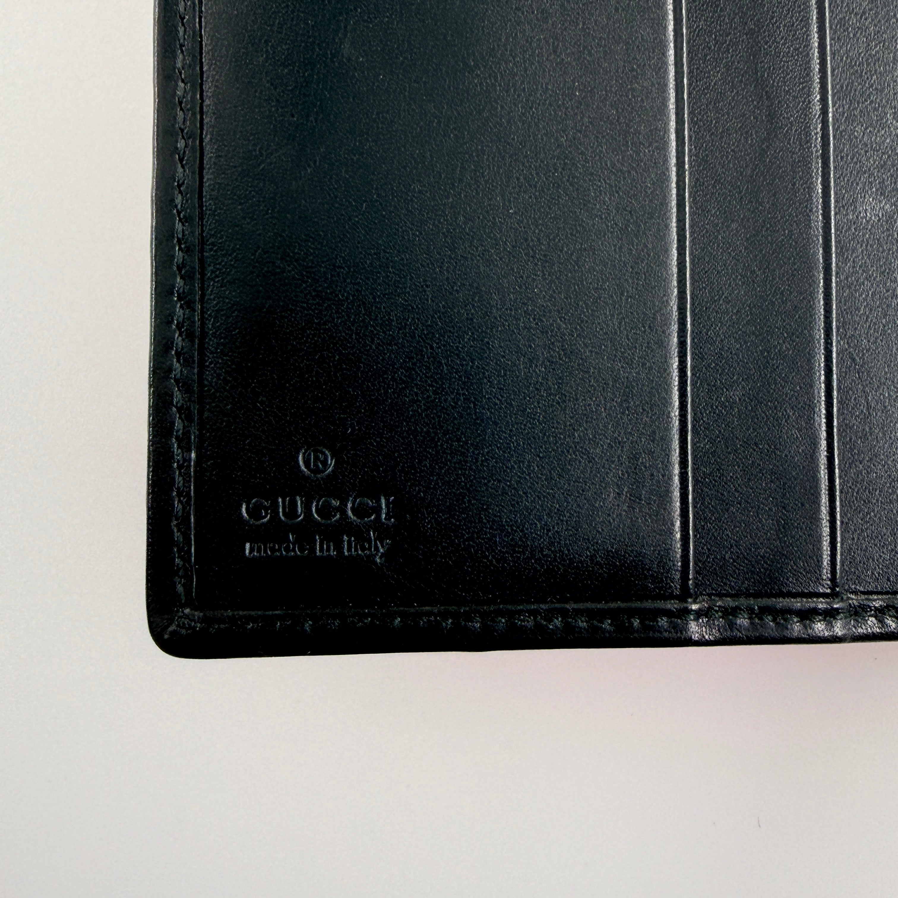 Gucci compact wallet with vibrant pink floral canvas, black leather trim and a silver-tone clasp, front view.