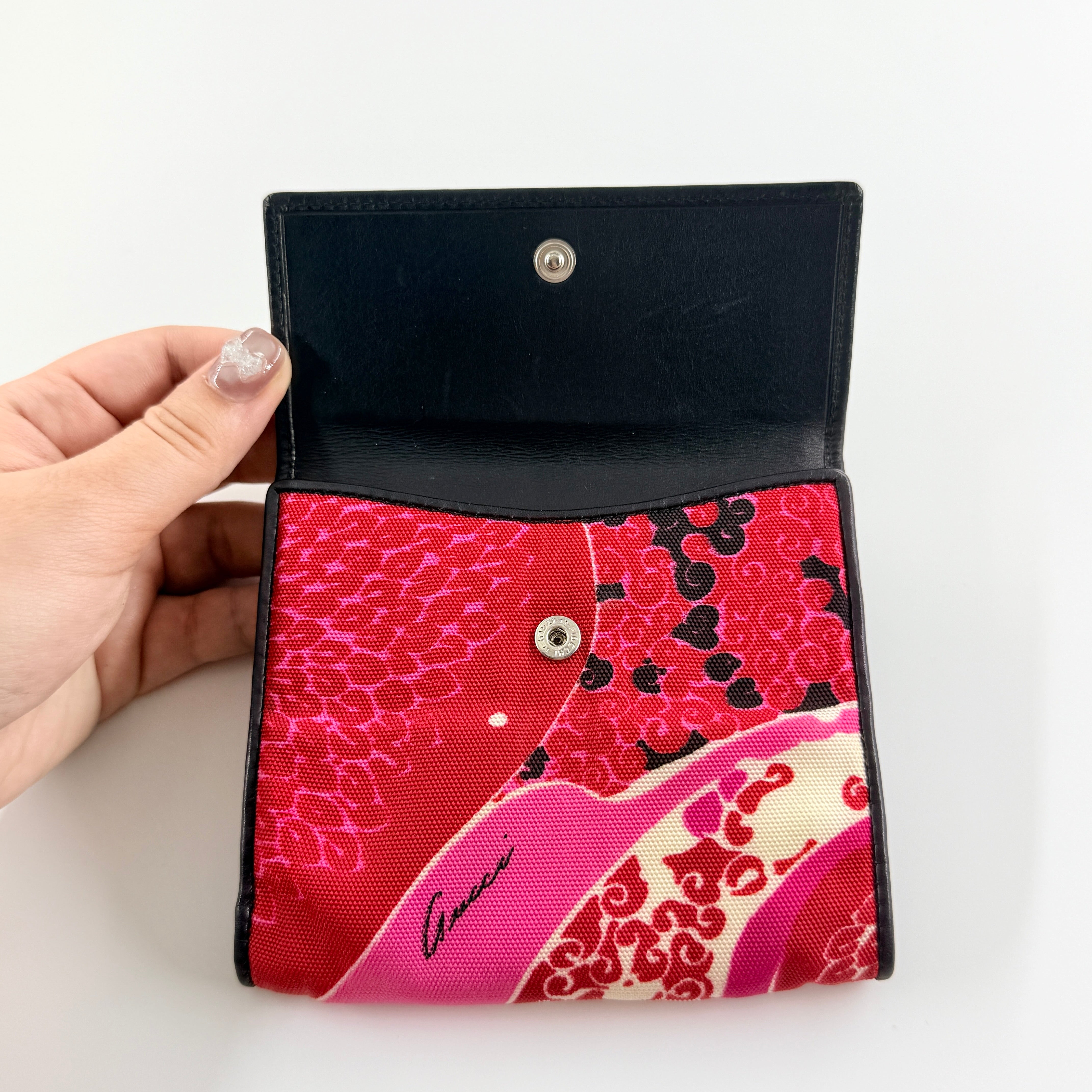 Gucci compact wallet with vibrant pink floral canvas, black leather trim and a silver-tone clasp, front view.