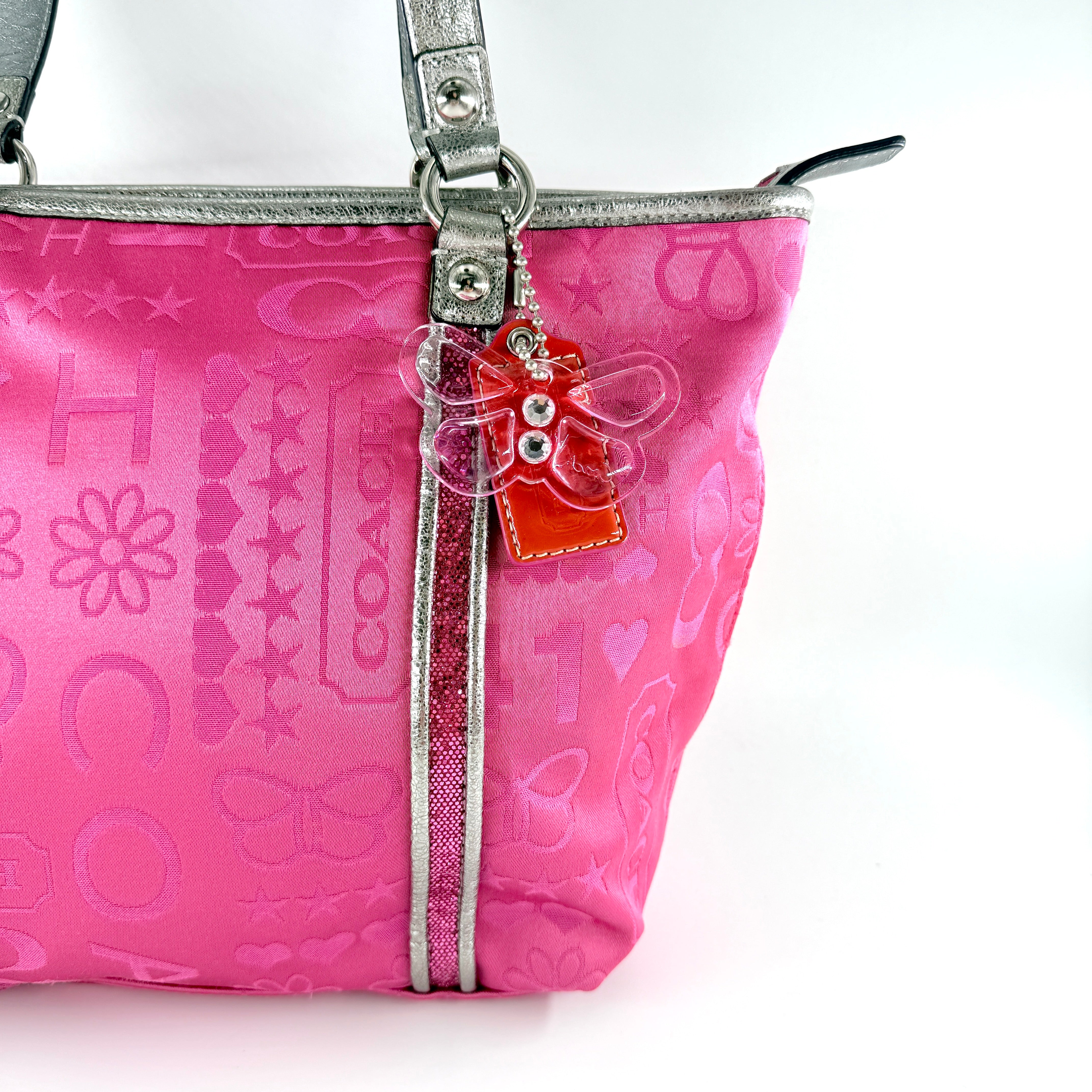 Coach Poppy Bandana Glitter Graffiti Tote Bag in vibrant pink with metallic silver handles, adorned with glitter accents and butterfly charm.
