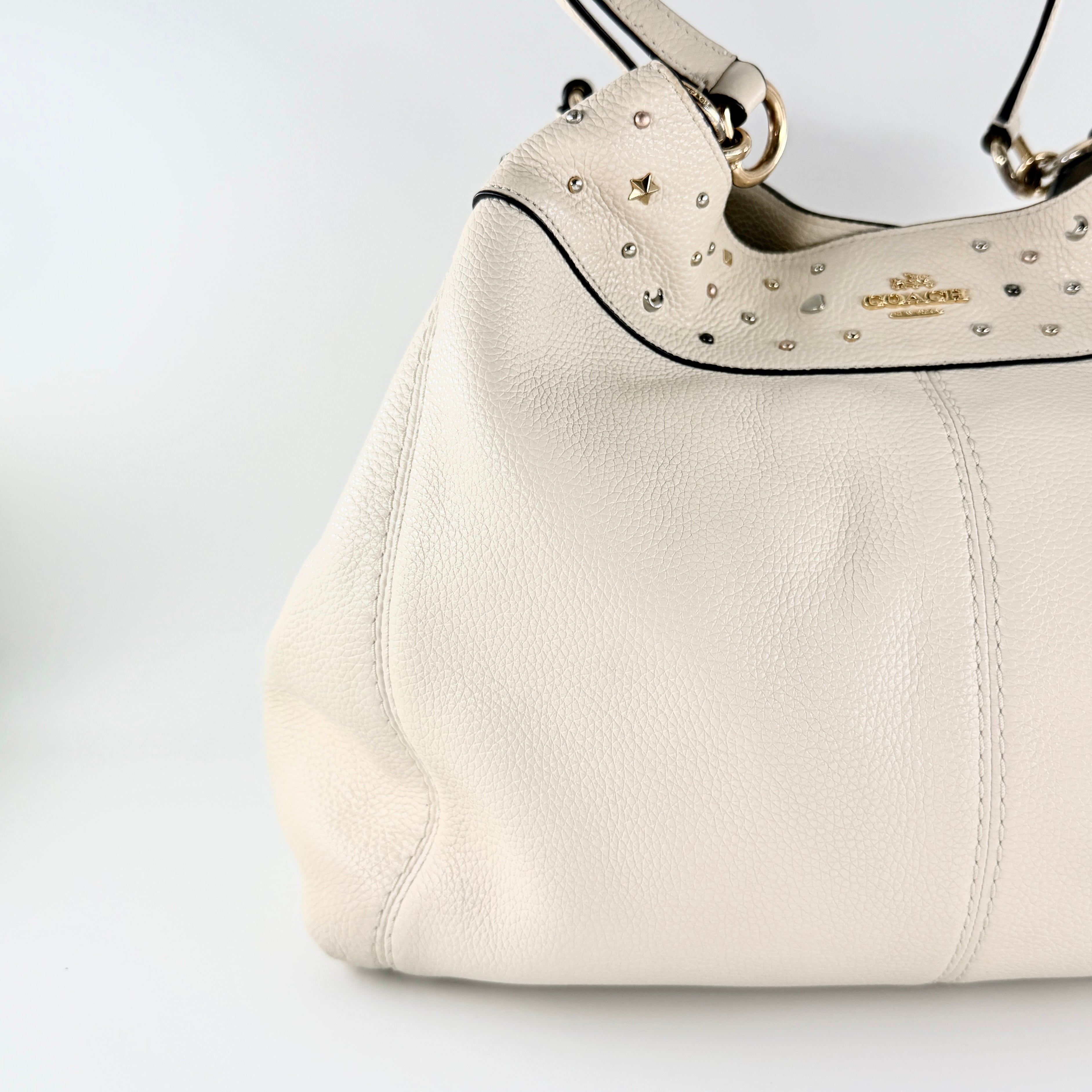 Coach Lexy Stardust Studded Chalk Hobo in ivory pebbled leather, adorned with mixed metal studs and dual handles.