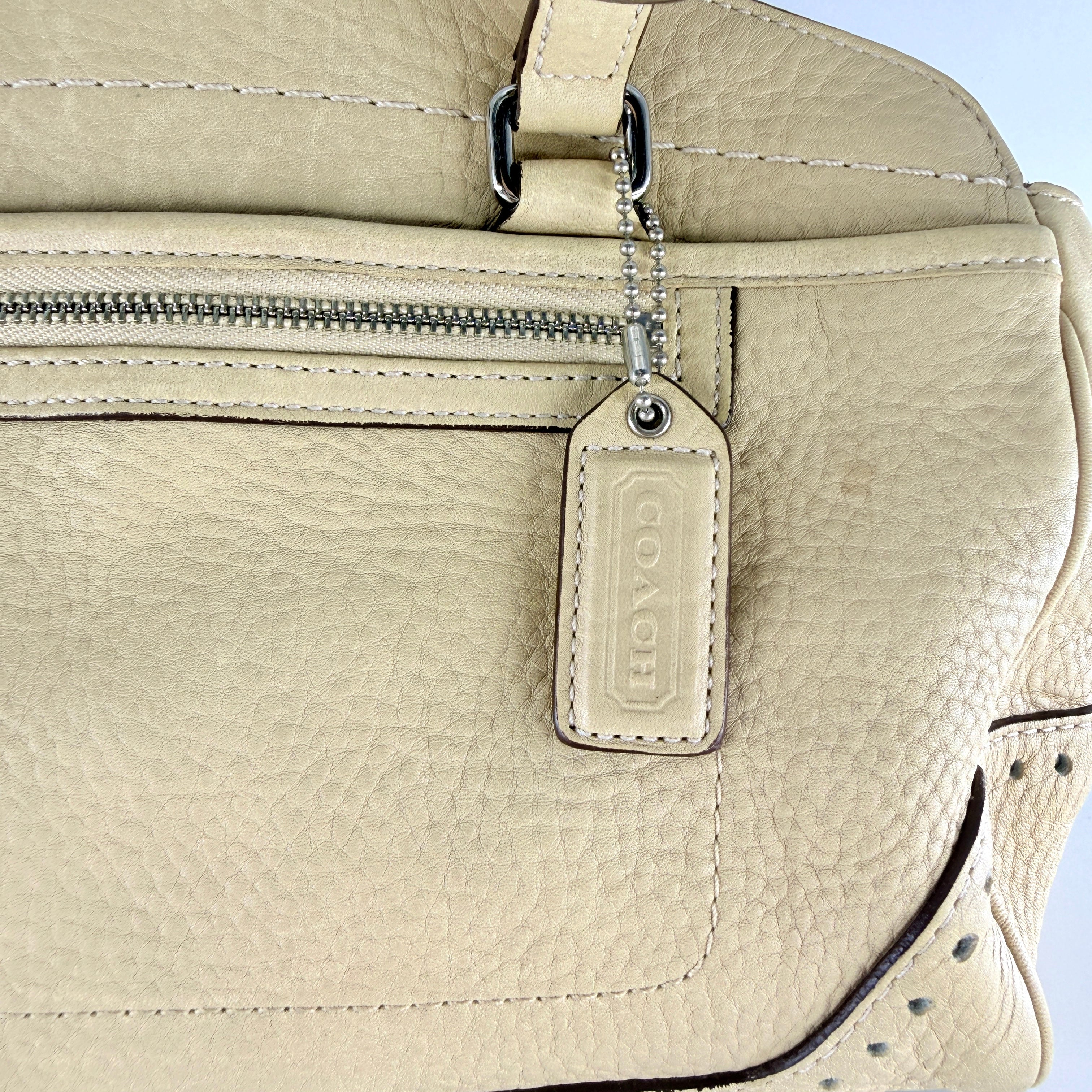 Coach Hampton Sand Satchel in beige pebbled leather with structured dual handles, front zip pocket, and silver-tone hardware.