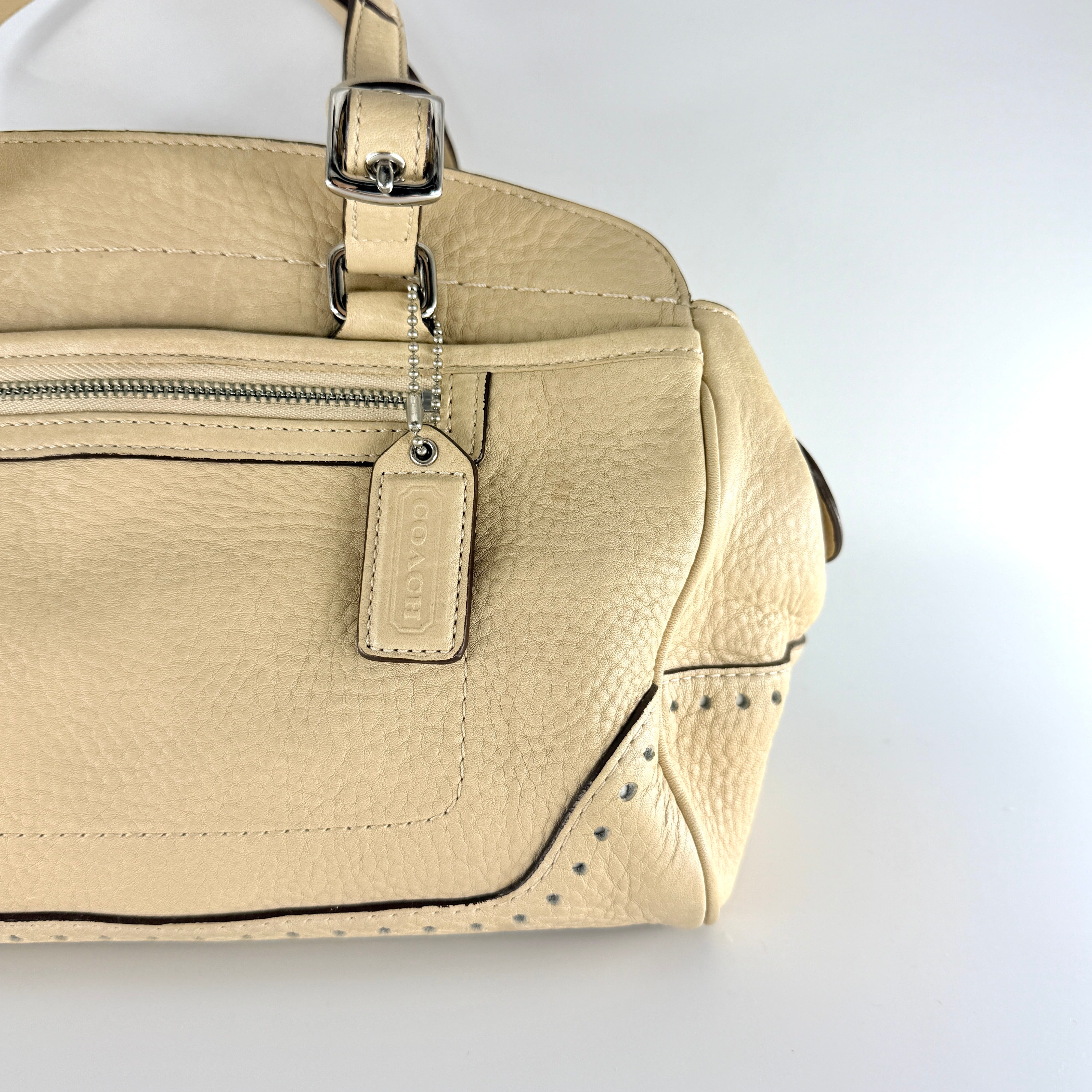 Coach Hampton Sand Satchel in beige pebbled leather with structured dual handles, front zip pocket, and silver-tone hardware.