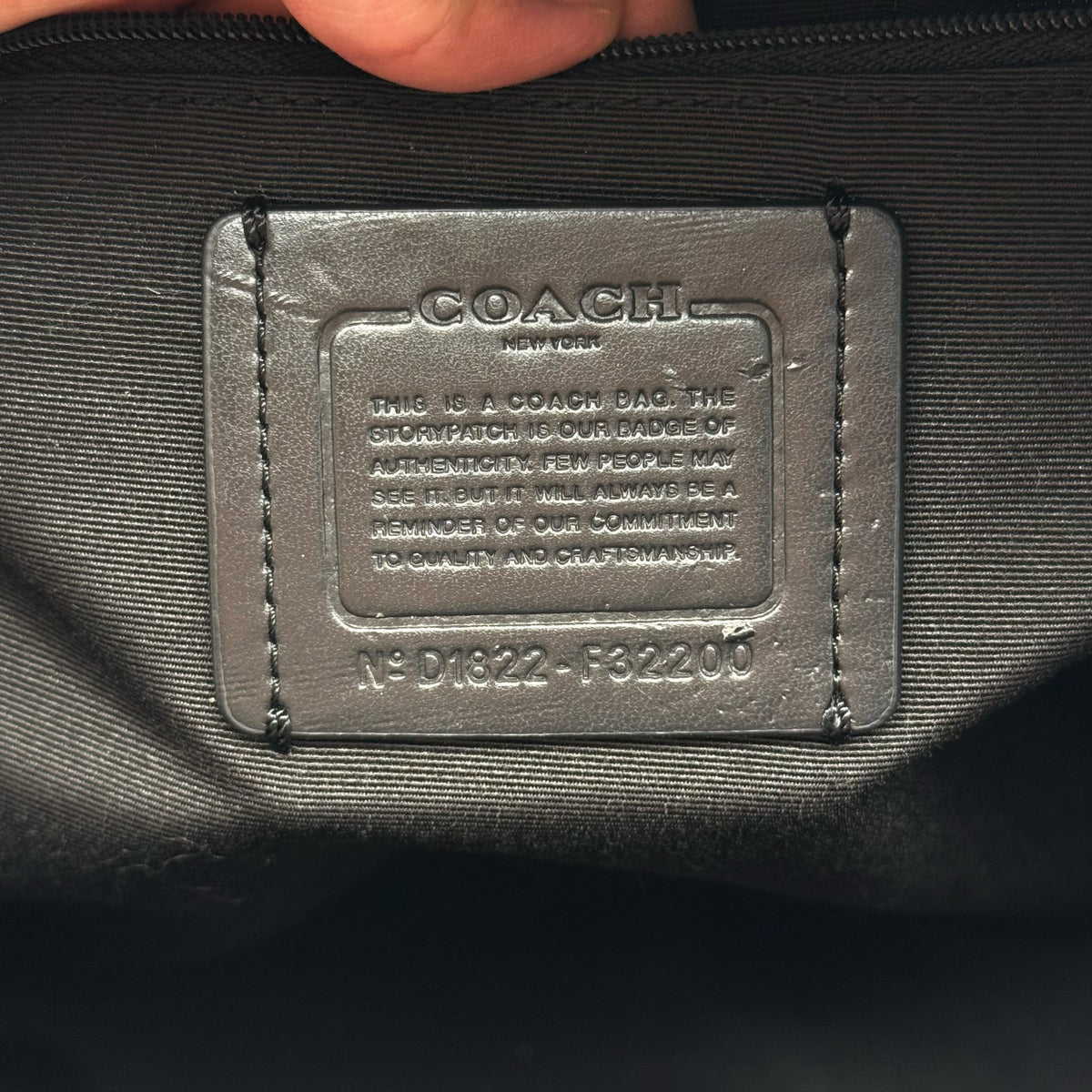 Coach Signature Charlie Backpack in brown and black canvas with gold-tone hardware and front zip pocket.