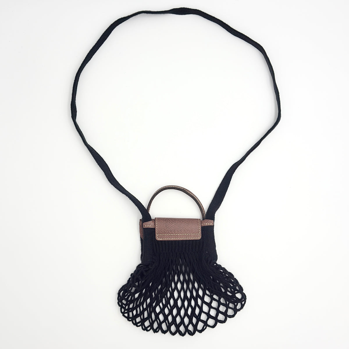 Longchamp Le Pliage Filet XS mesh bag in black and brown leather with a long strap, styled simply against a white background.