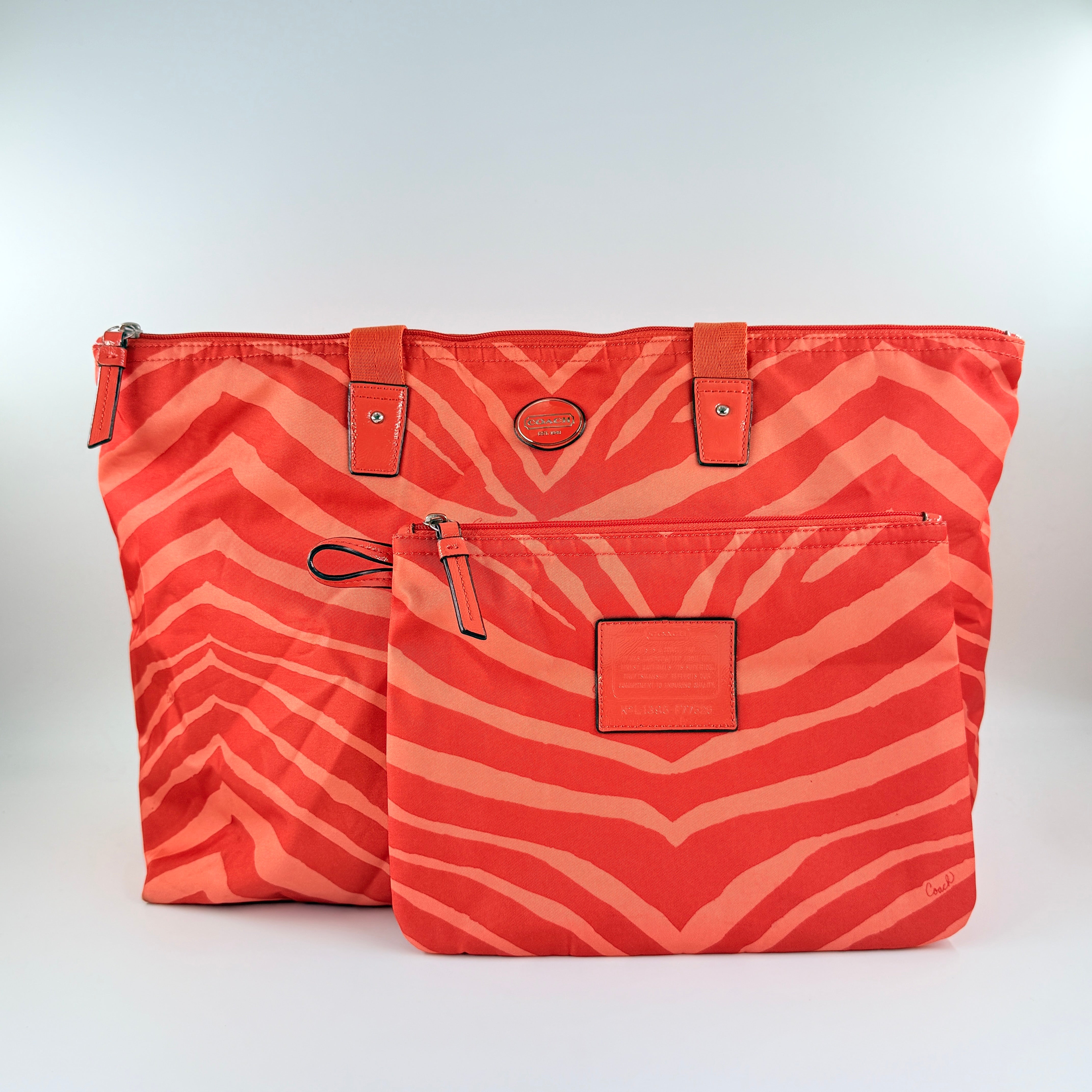 Coach Getaway Weekender tote and matching pouch in orange zebra print, with structured silhouette and bold colour.