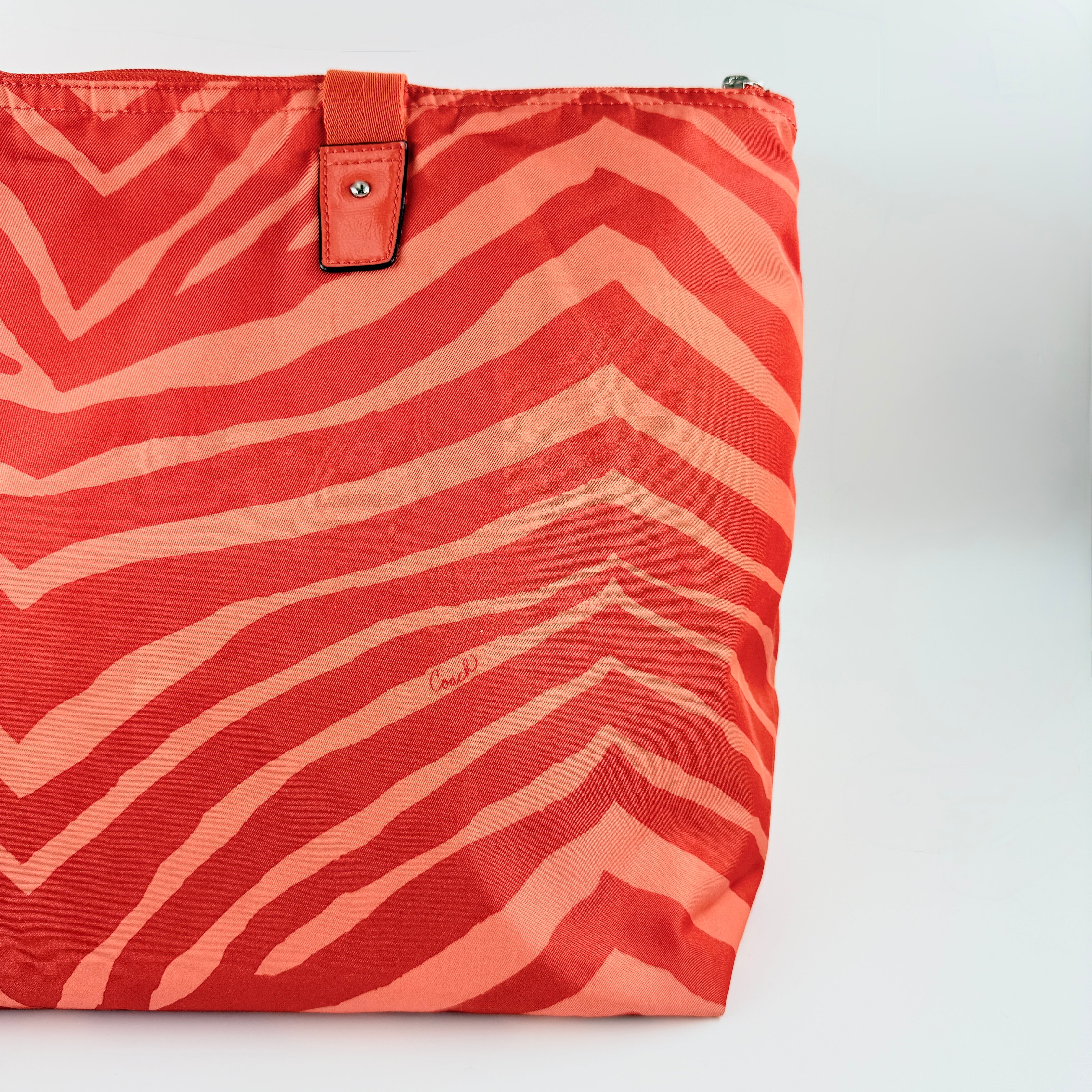 Coach Getaway Weekender tote and matching pouch in orange zebra print, with structured silhouette and bold colour.