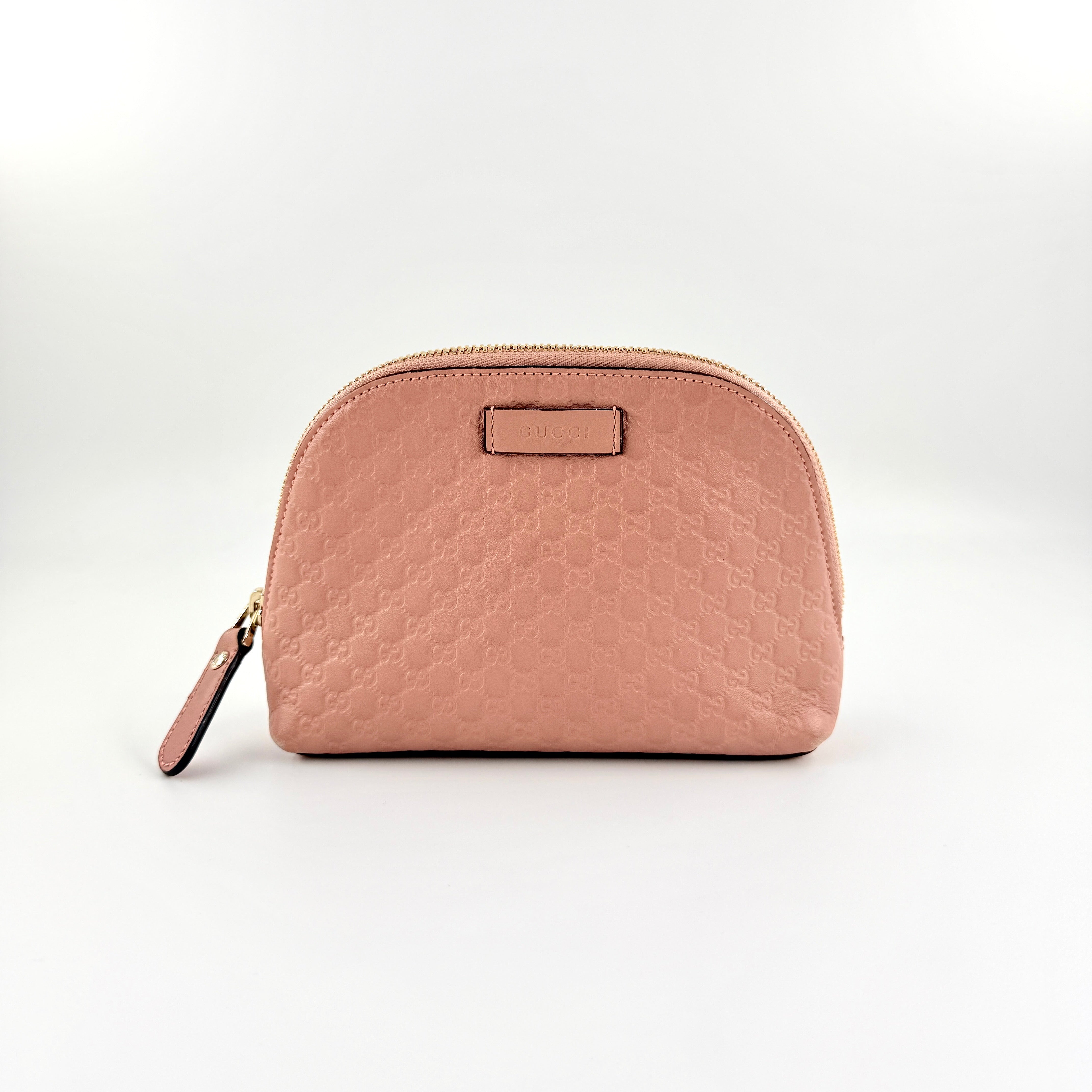 Gucci GG Monogram Guccissima cosmetic pouch in blush pink leather with signature embossed motif and gold-tone zip hardware.
