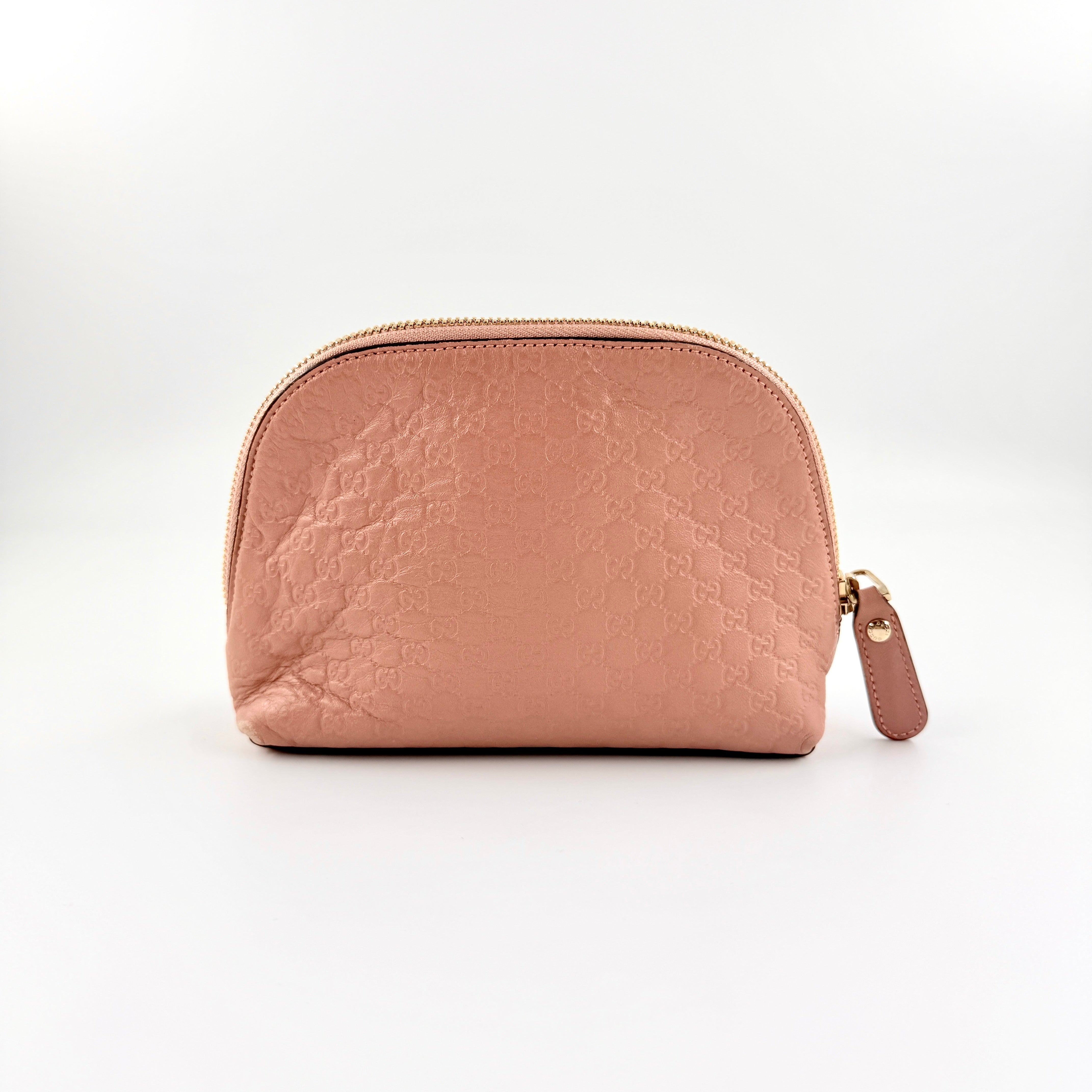 Gucci GG Monogram Guccissima cosmetic pouch in blush pink leather with signature embossed motif and gold-tone zip hardware.