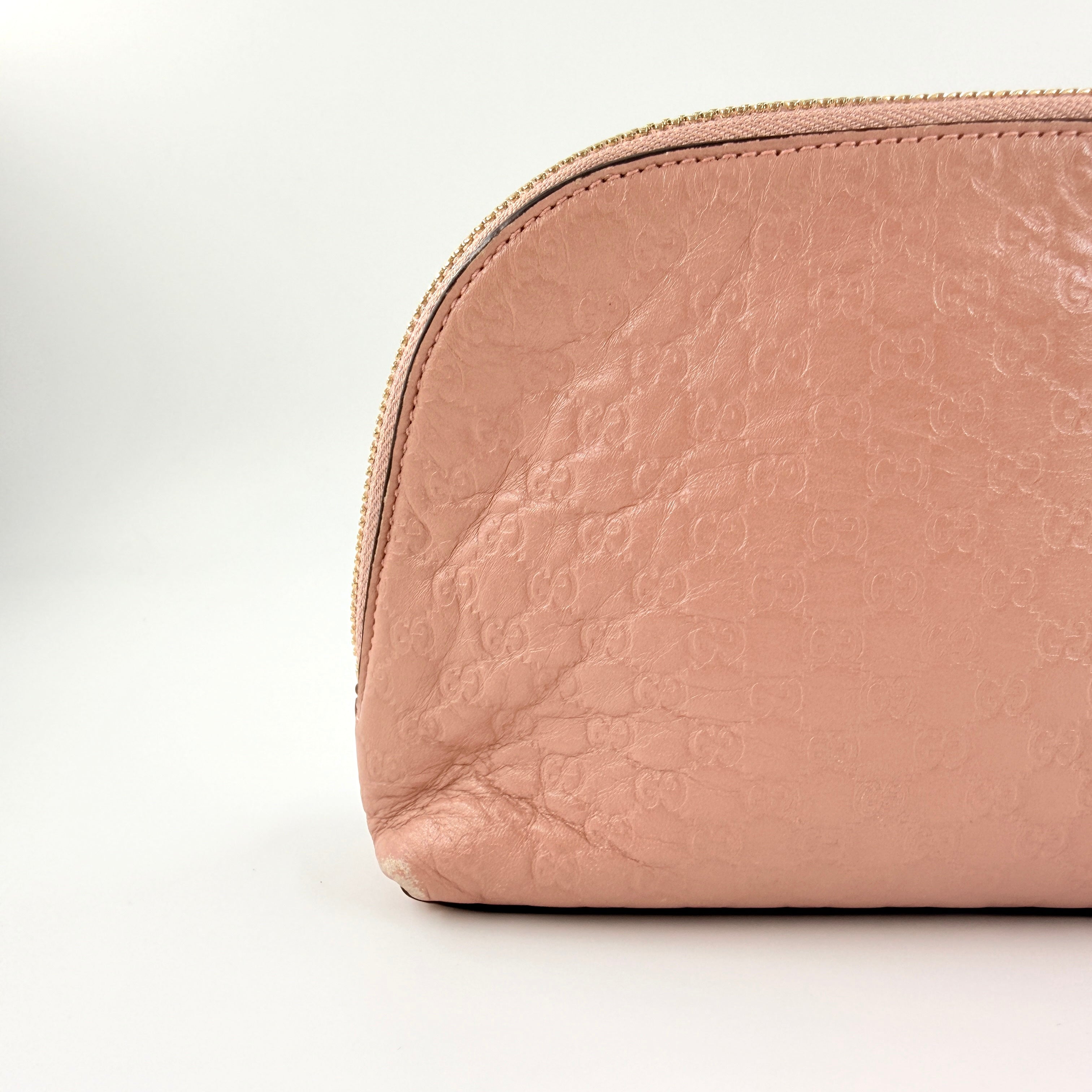 Gucci GG Monogram Guccissima cosmetic pouch in blush pink leather with signature embossed motif and gold-tone zip hardware.