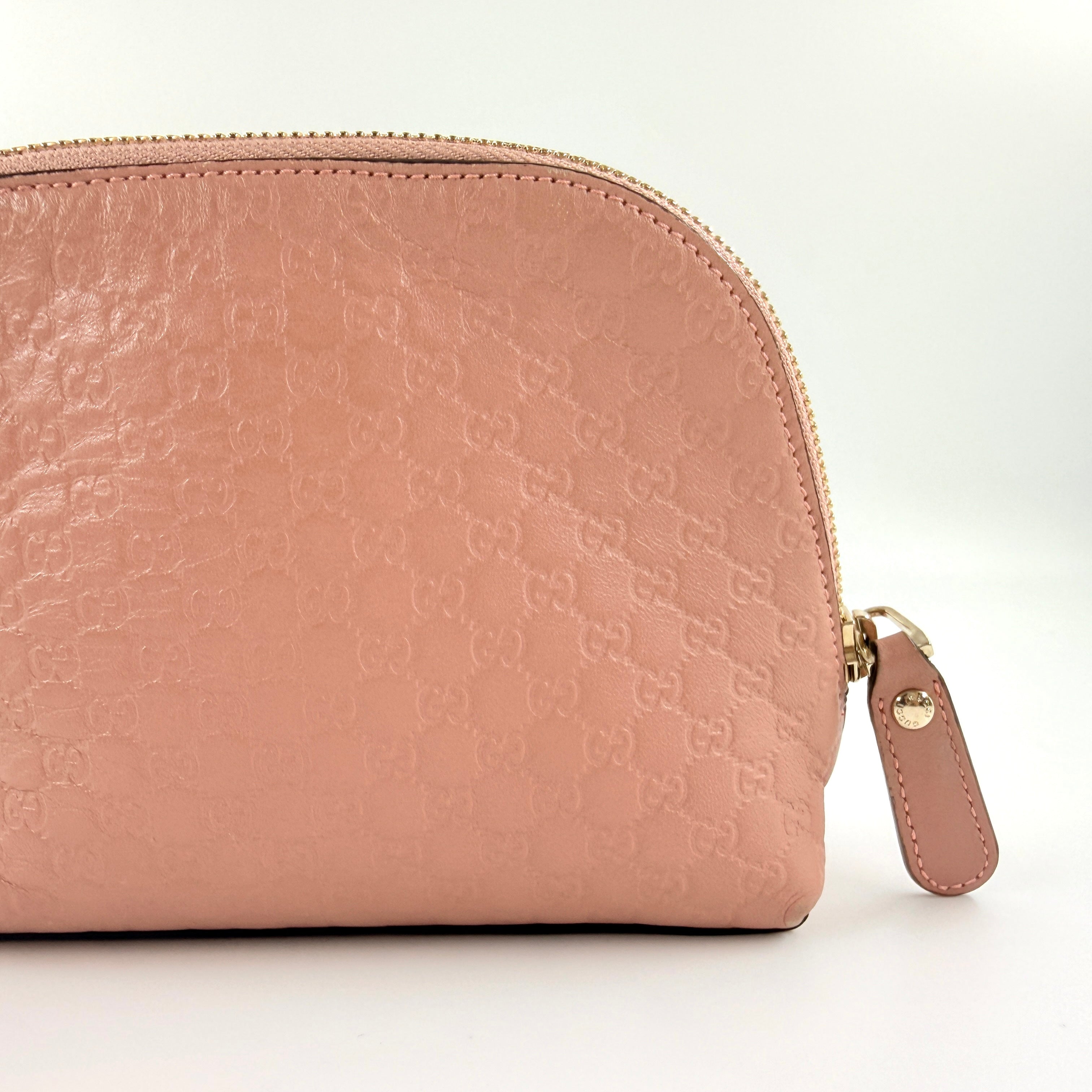 Gucci GG Monogram Guccissima cosmetic pouch in blush pink leather with signature embossed motif and gold-tone zip hardware.
