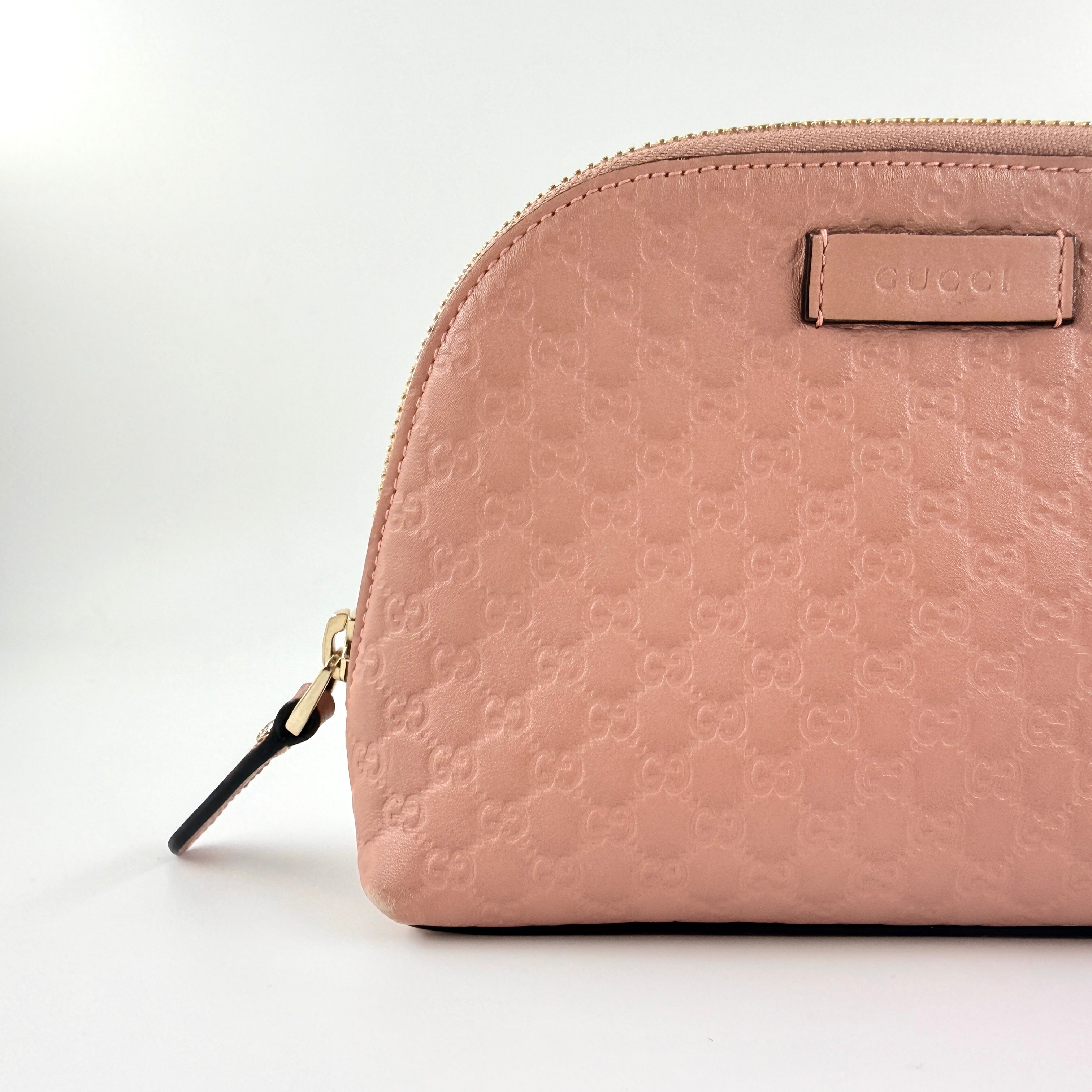 Gucci GG Monogram Guccissima cosmetic pouch in blush pink leather with signature embossed motif and gold-tone zip hardware.