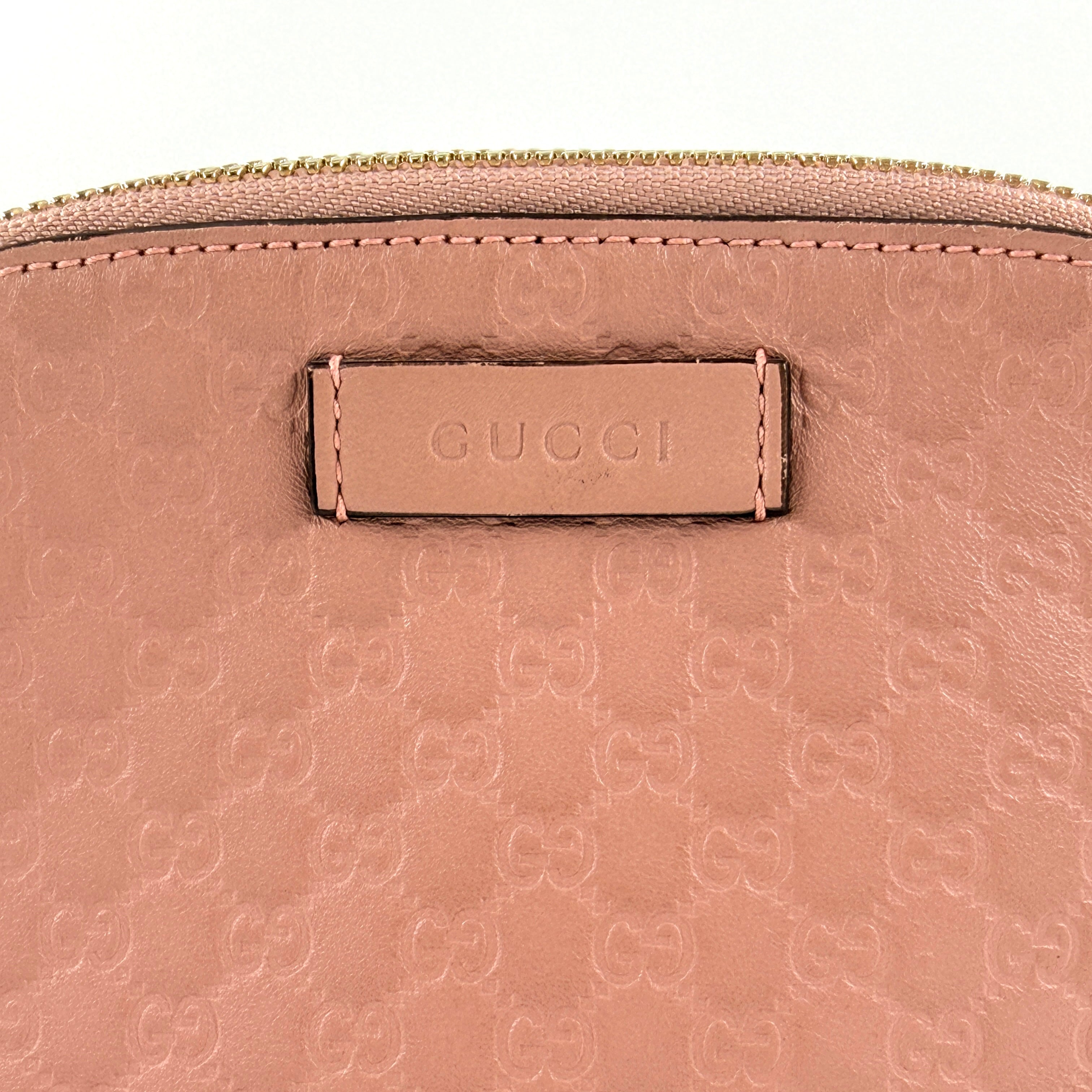 Gucci GG Monogram Guccissima cosmetic pouch in blush pink leather with signature embossed motif and gold-tone zip hardware.