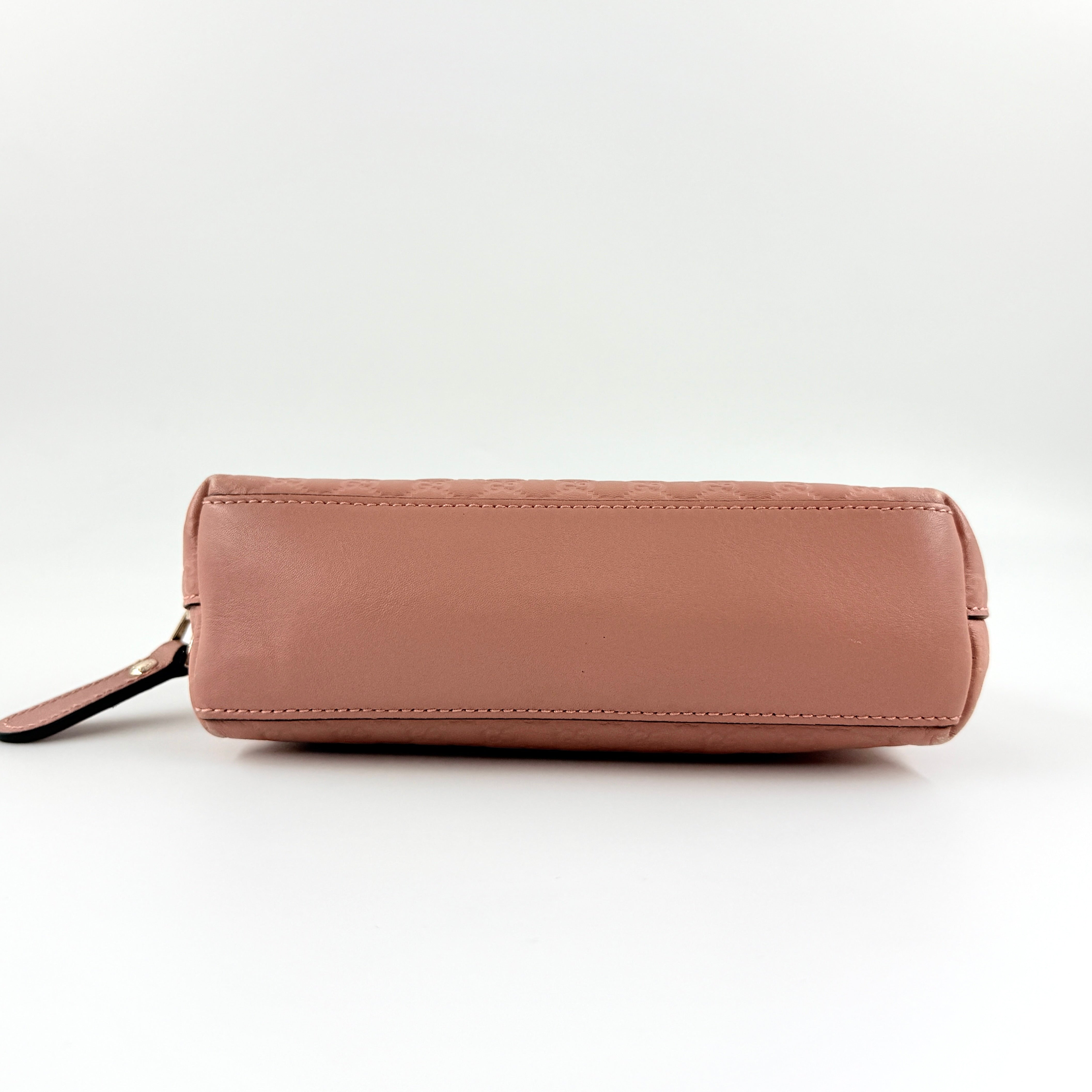 Gucci GG Monogram Guccissima cosmetic pouch in blush pink leather with signature embossed motif and gold-tone zip hardware.