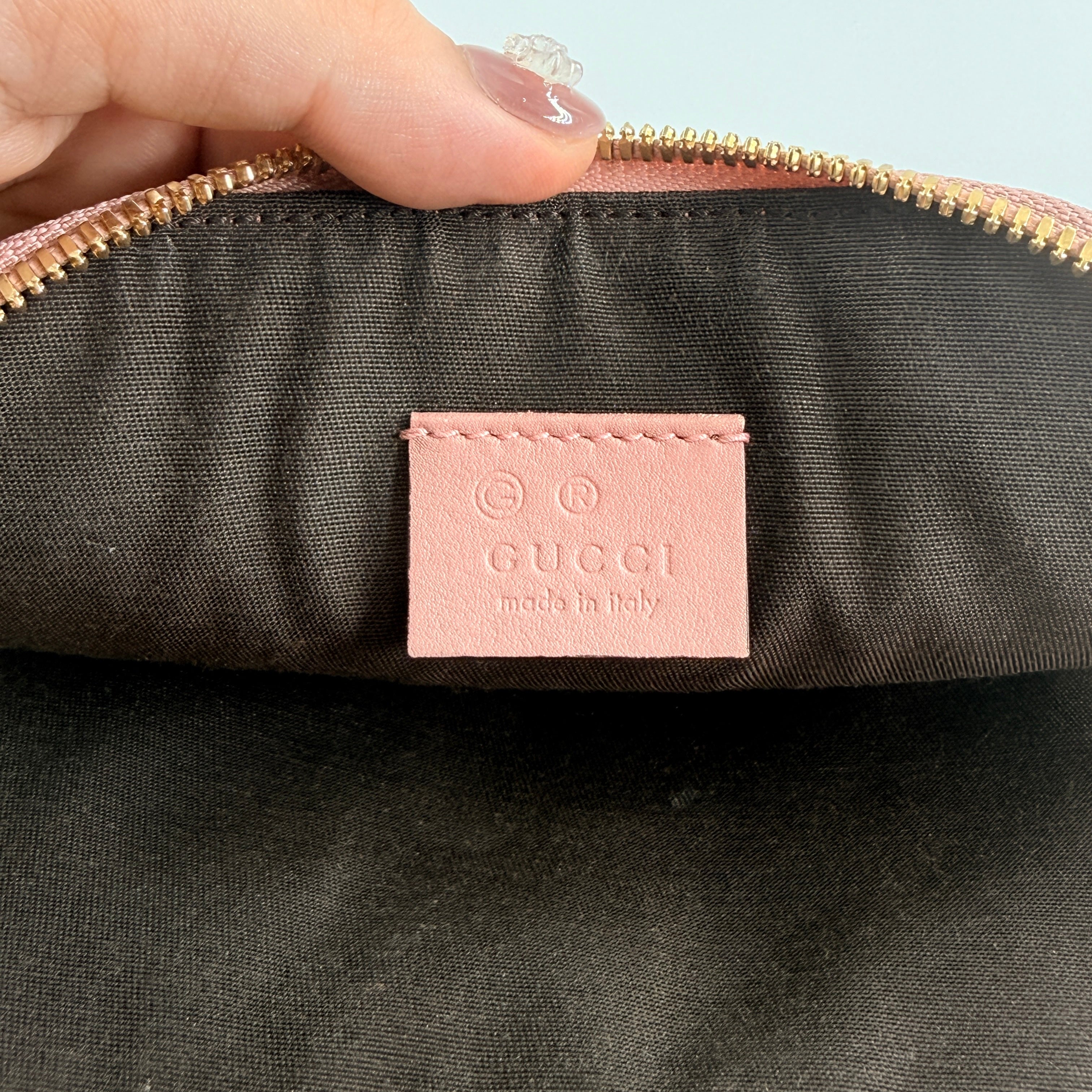 Gucci GG Monogram Guccissima cosmetic pouch in blush pink leather with signature embossed motif and gold-tone zip hardware.