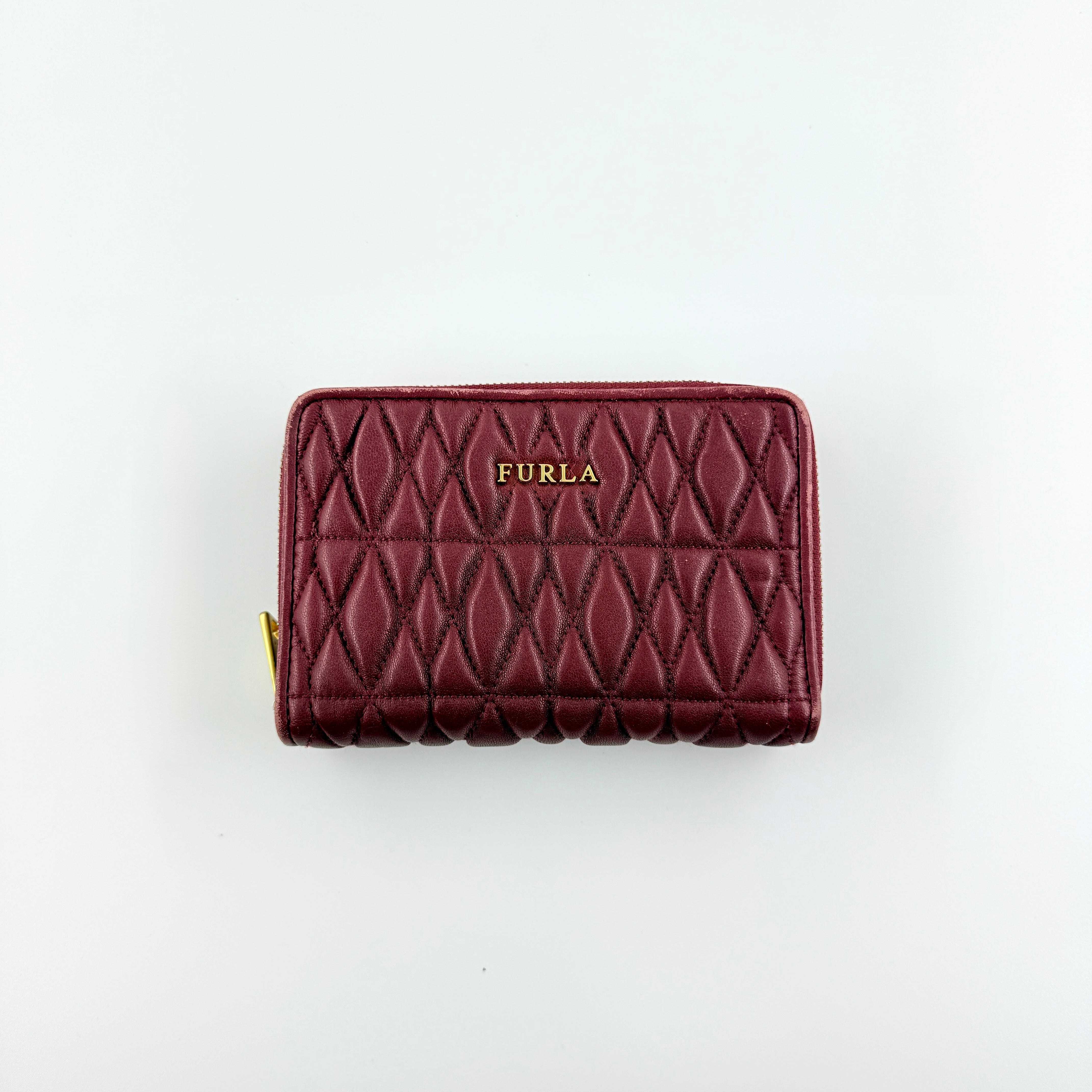 Furla quilted Cometa zip around wallet in deep burgundy leather with gold-tone hardware and diamond stitching.