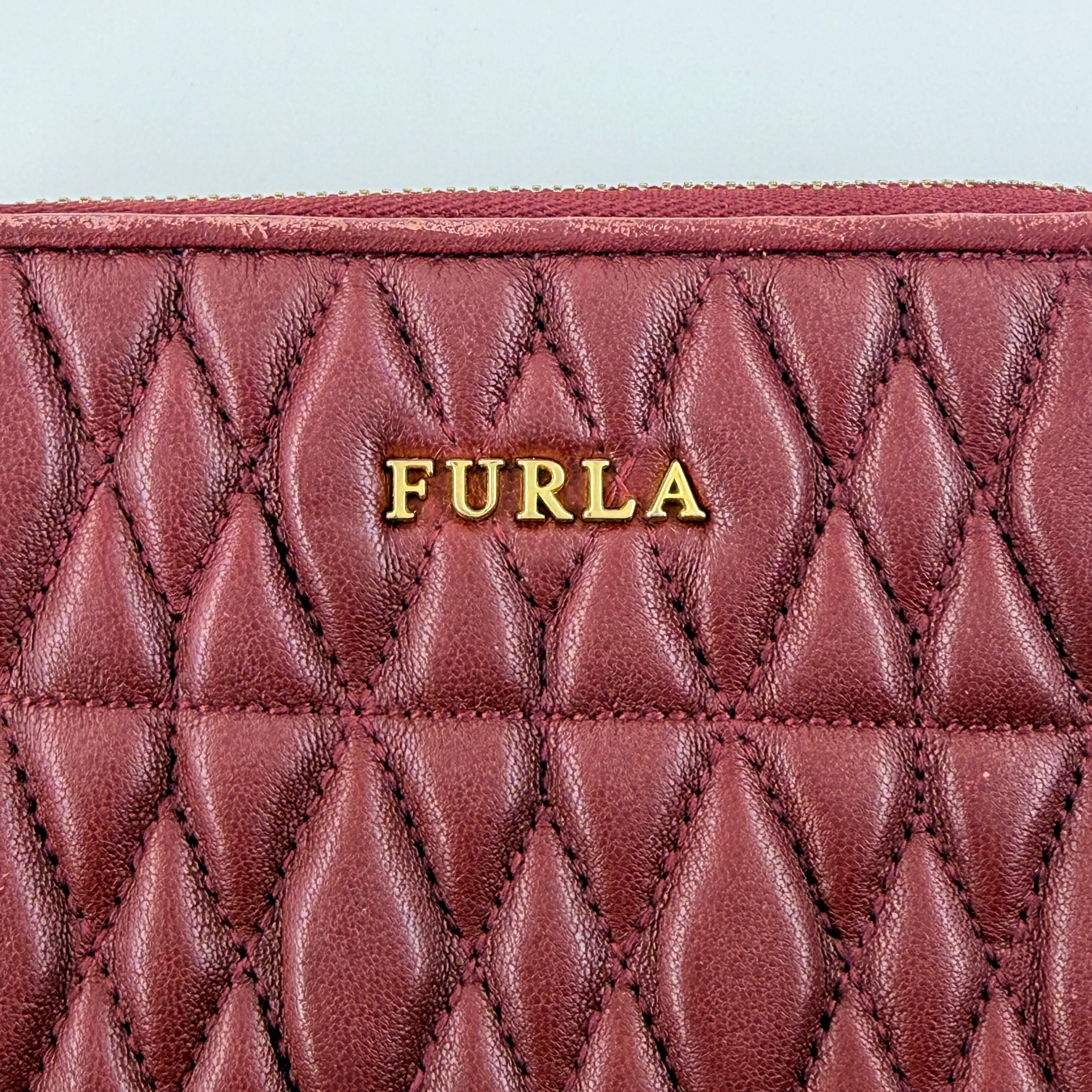 Furla quilted Cometa zip around wallet in deep burgundy leather with gold-tone hardware and diamond stitching.