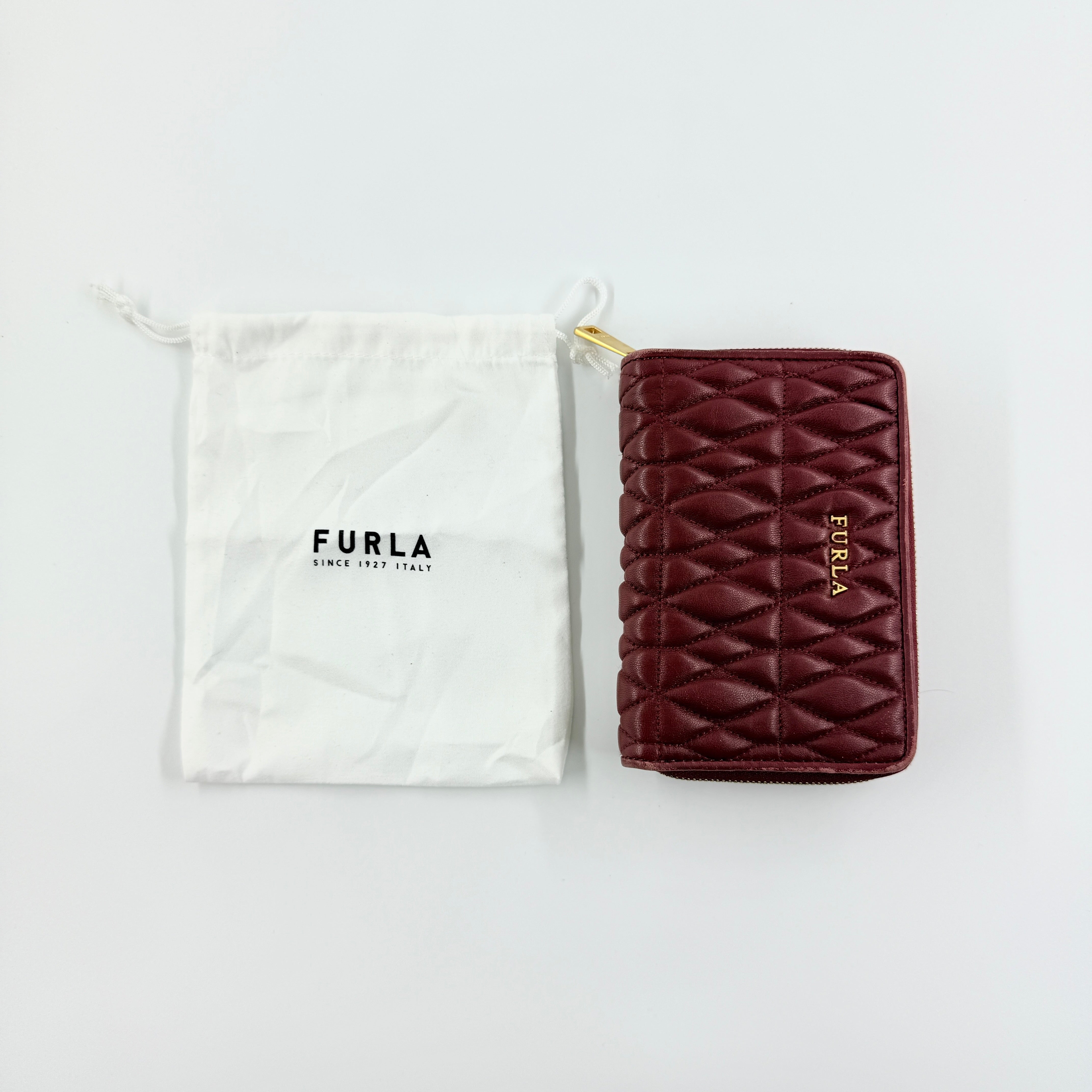 Furla quilted Cometa zip around wallet in deep burgundy leather with gold-tone hardware and diamond stitching.