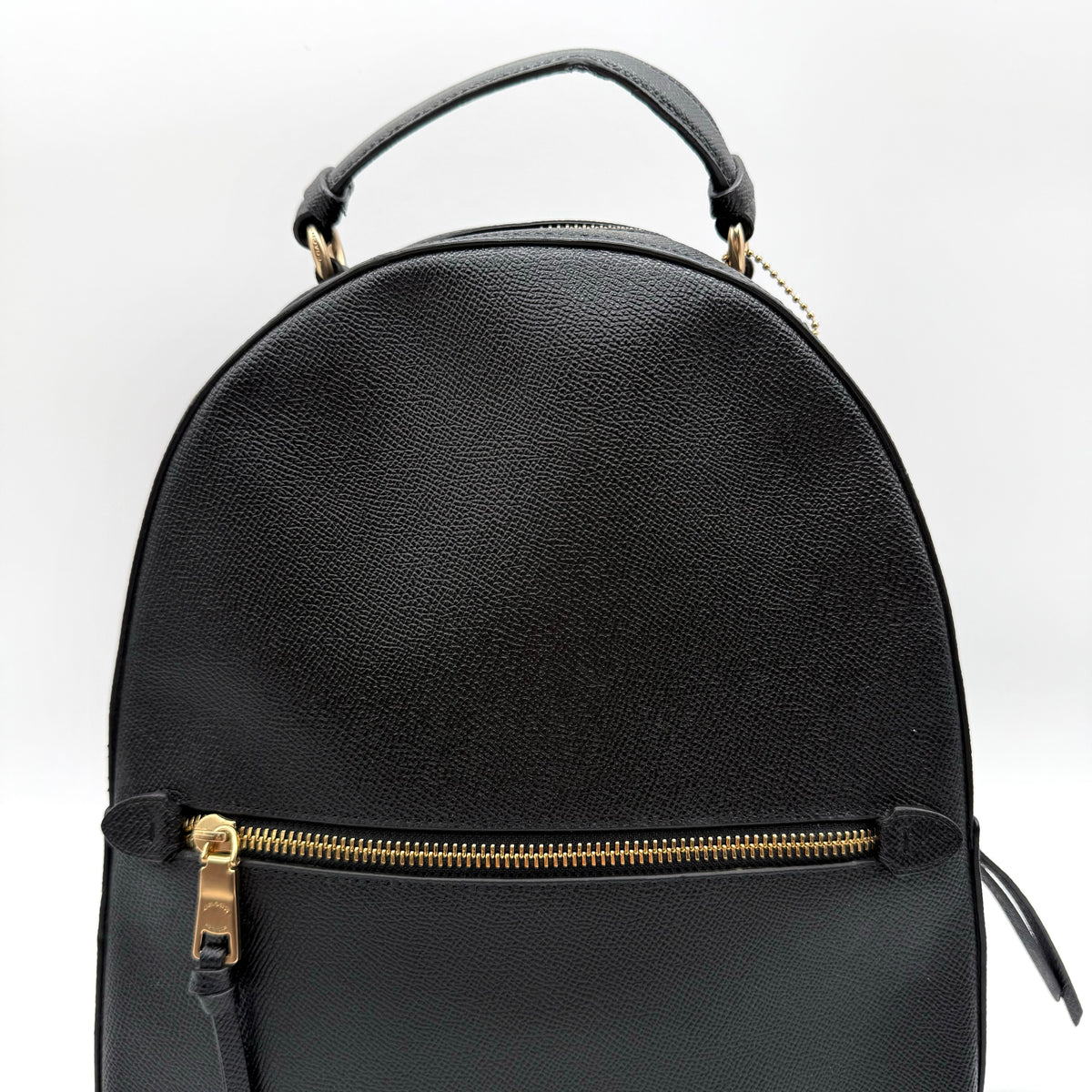 Coach Jordyn Leather Backpack in black grained leather with gold-tone hardware and minimal branding, photographed on white background.
