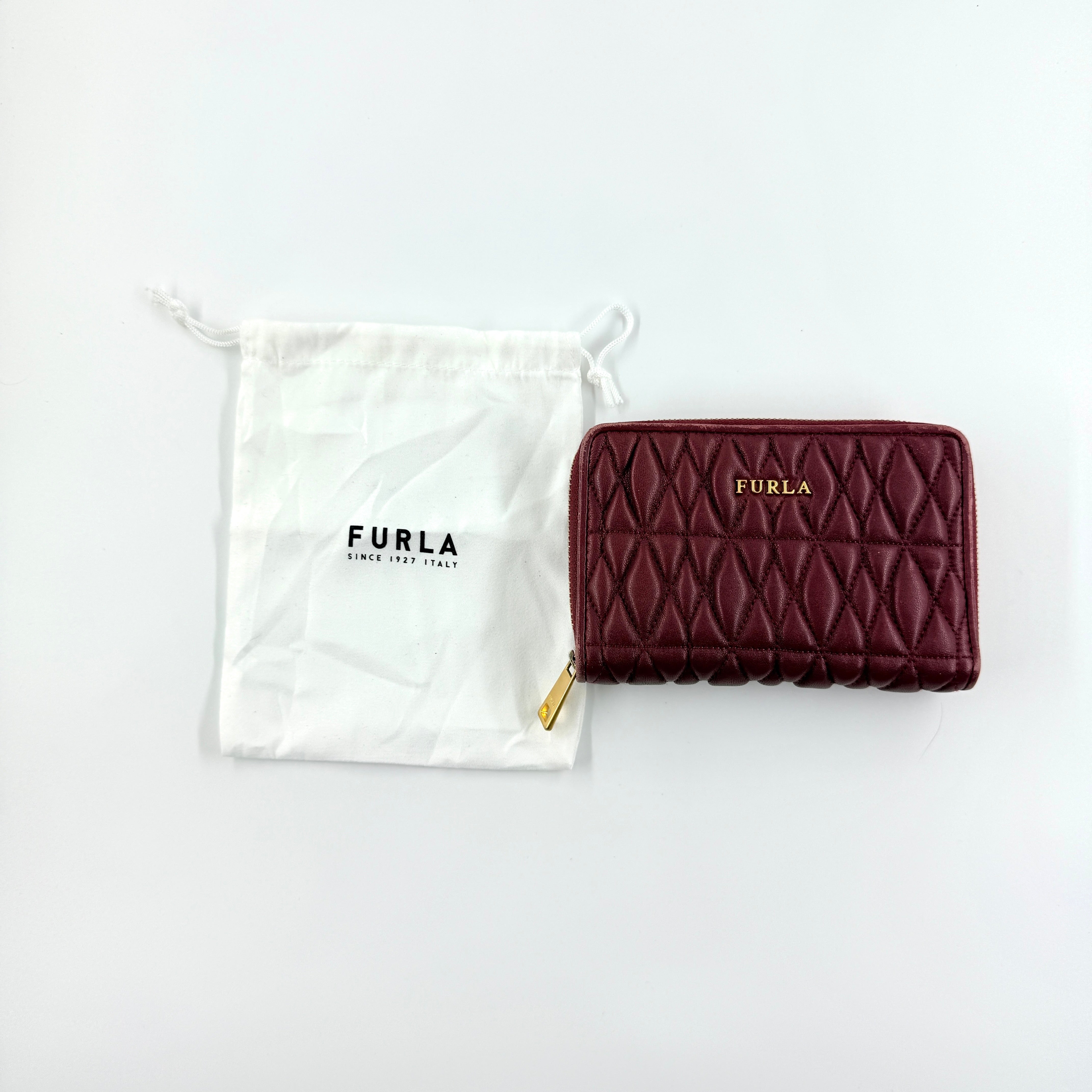 Furla quilted Cometa zip around wallet in deep burgundy leather with gold-tone hardware and diamond stitching.