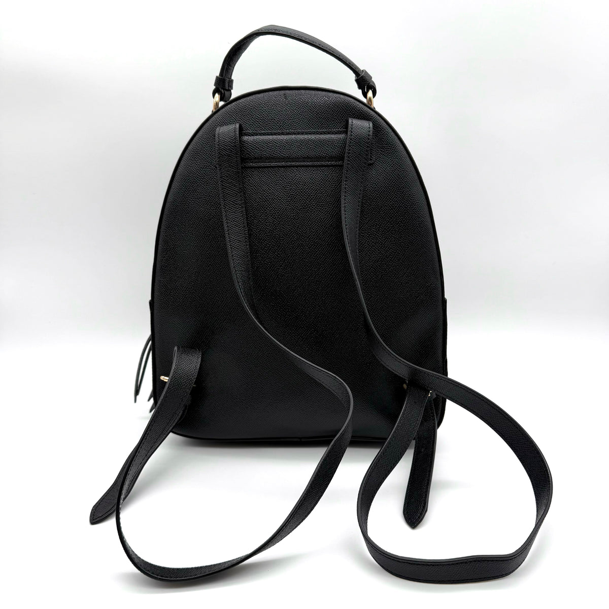 Coach Jordyn Leather Backpack in black grained leather with gold-tone hardware and minimal branding, photographed on white background.