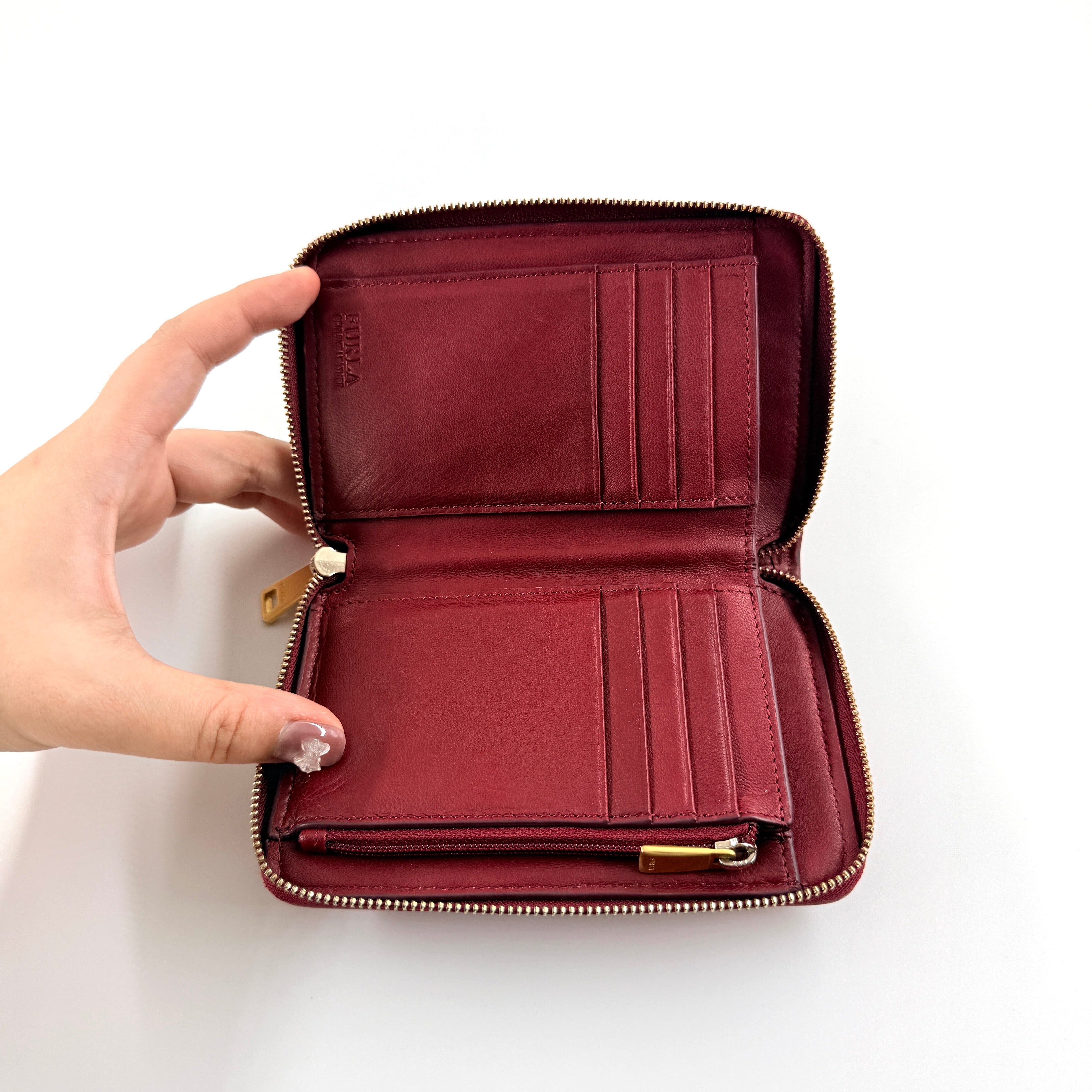 Furla quilted Cometa zip around wallet in deep burgundy leather with gold-tone hardware and diamond stitching.