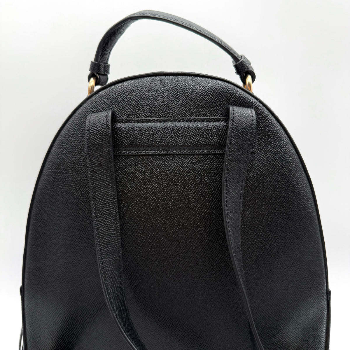Coach Jordyn Leather Backpack in black grained leather with gold-tone hardware and minimal branding, photographed on white background.