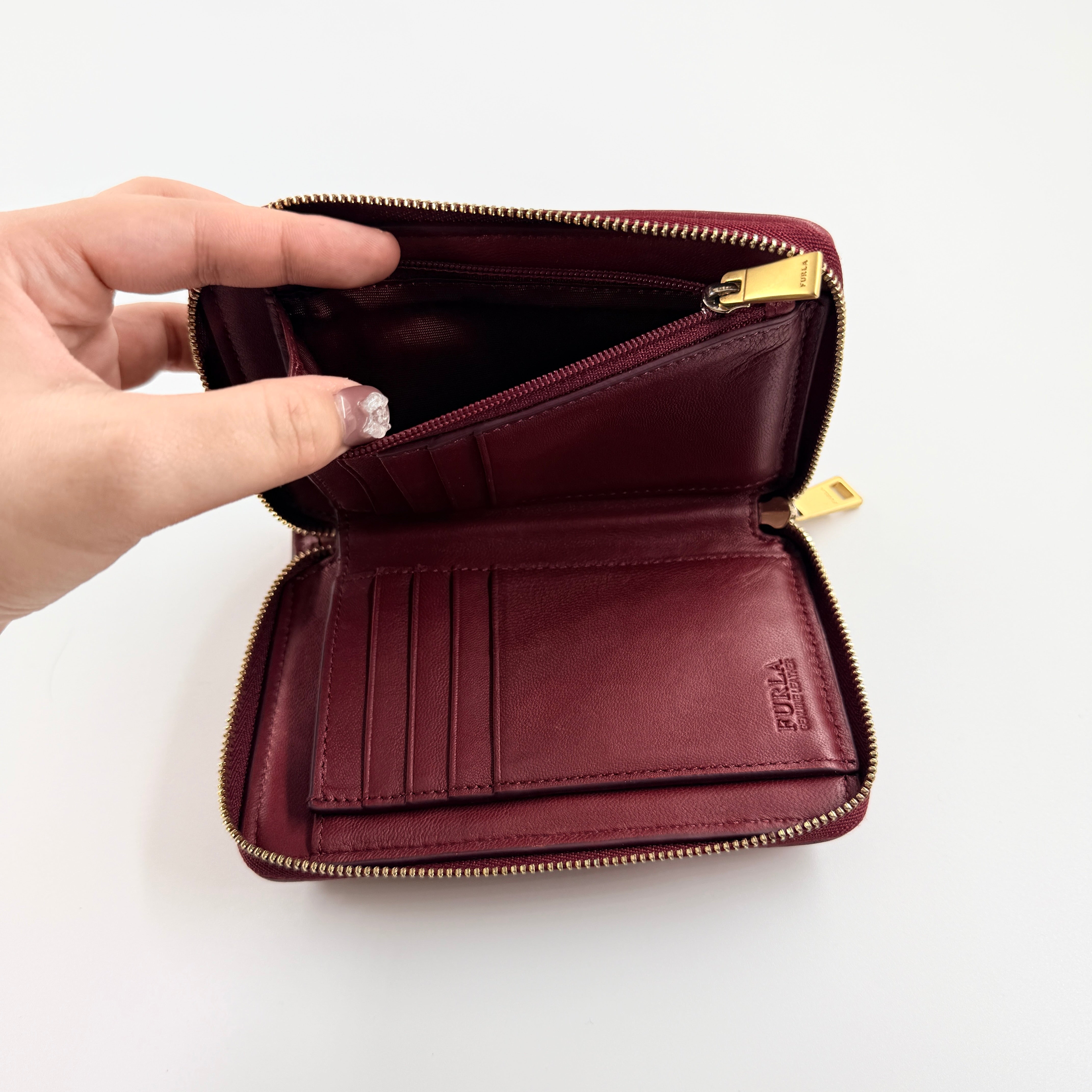 Furla quilted Cometa zip around wallet in deep burgundy leather with gold-tone hardware and diamond stitching.