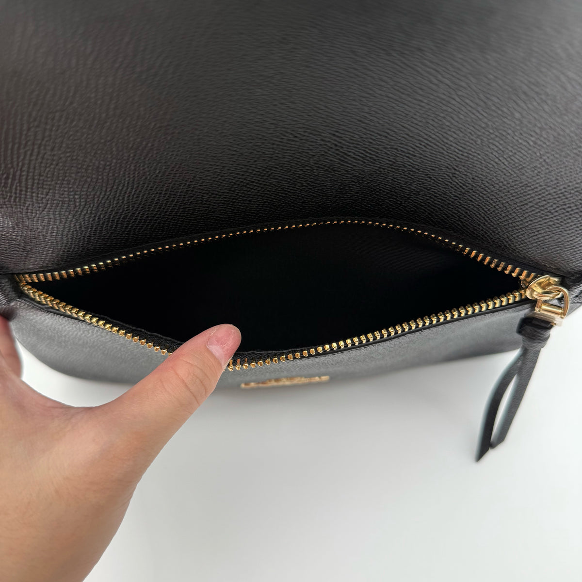 Coach Jordyn Leather Backpack in black grained leather with gold-tone hardware and minimal branding, photographed on white background.