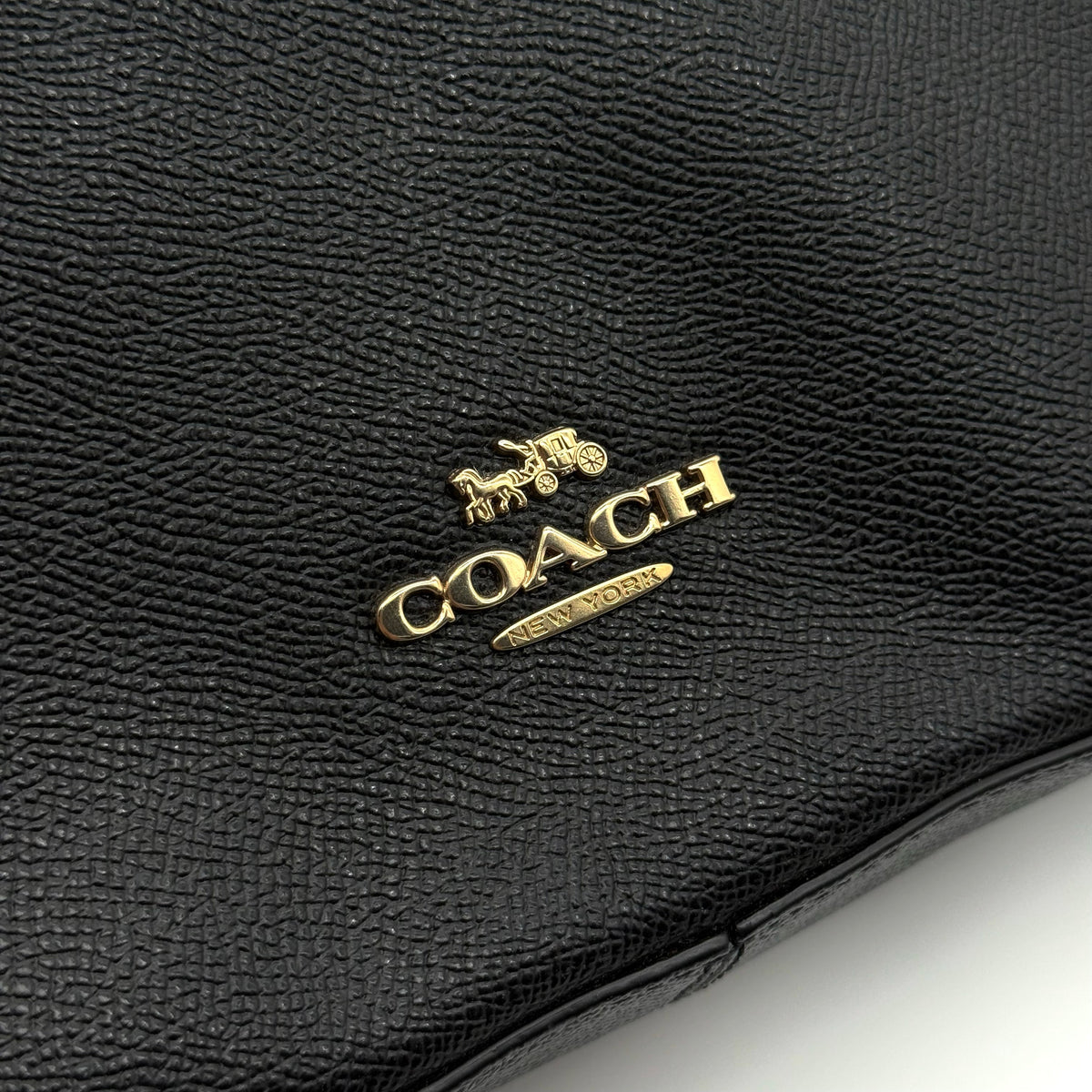 Coach Jordyn Leather Backpack in black grained leather with gold-tone hardware and minimal branding, photographed on white background.