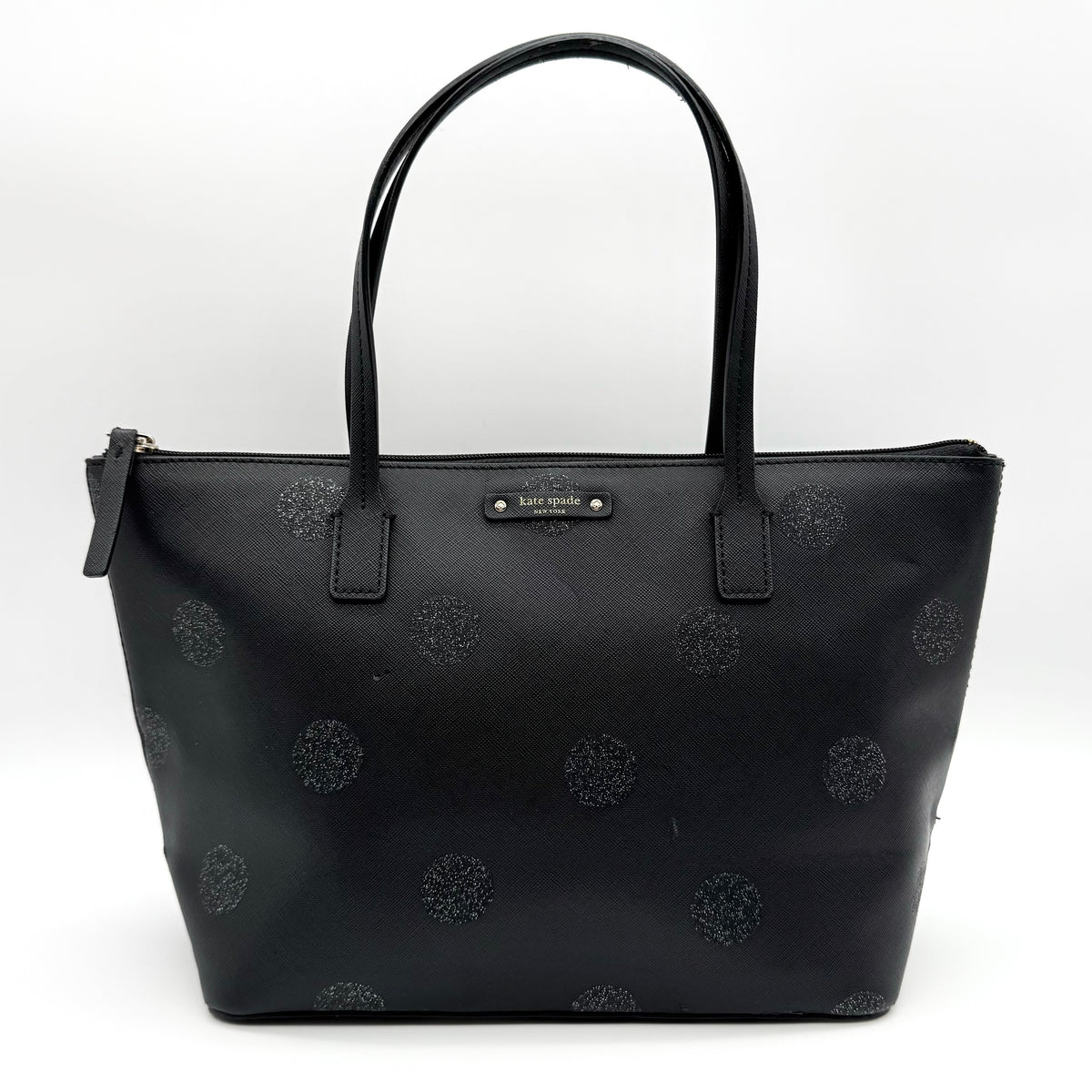 Front view of a Kate Spade black tote bag with glitter polka dots and dual handles.