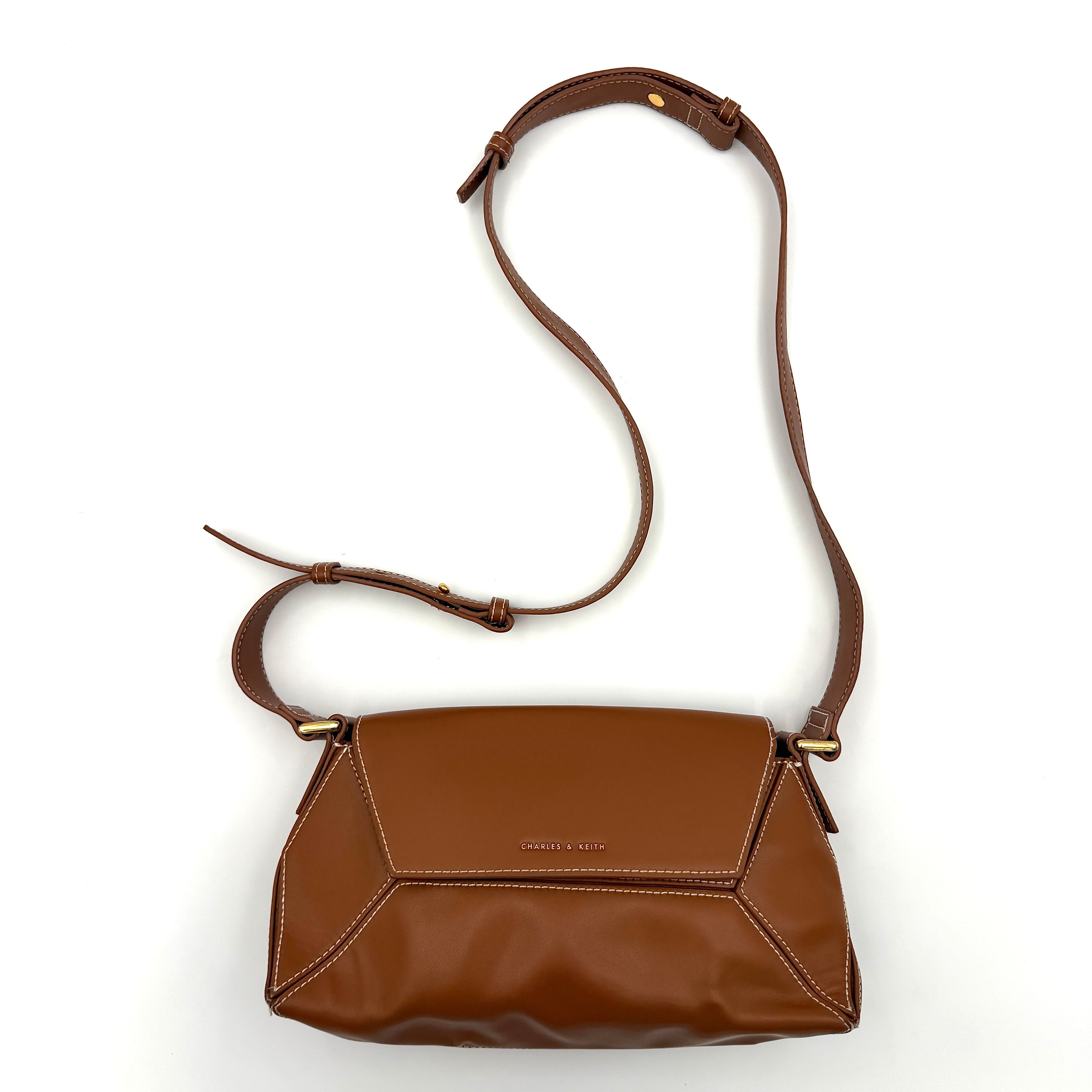 Charles & Keith Nasrin Geometric Crossbody Bag in brown faux leather with angular stitching, gold-tone hardware, and adjustable strap.
