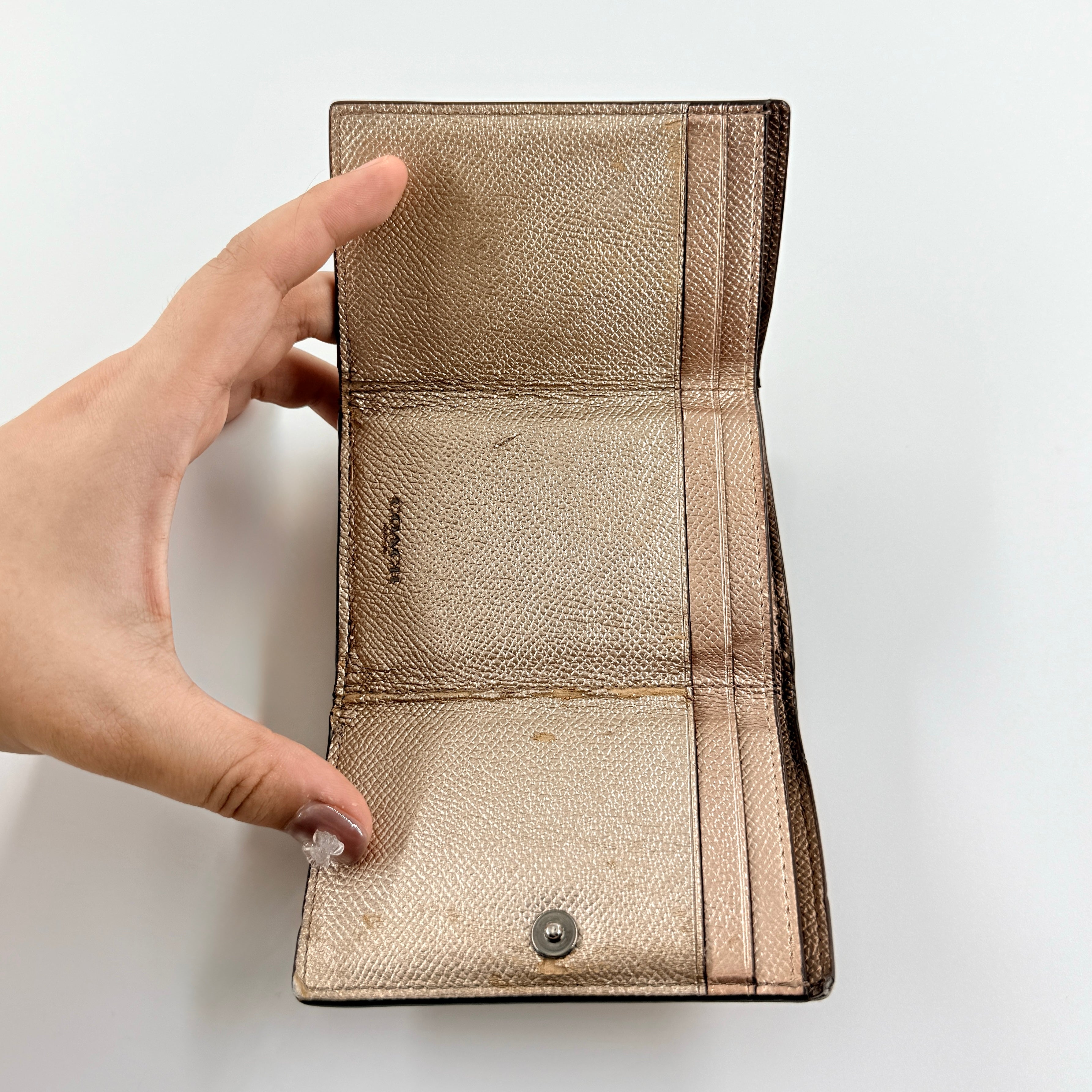 Coach metallic gold small flap wallet with silver logo plaque and crosshatch textured leather.