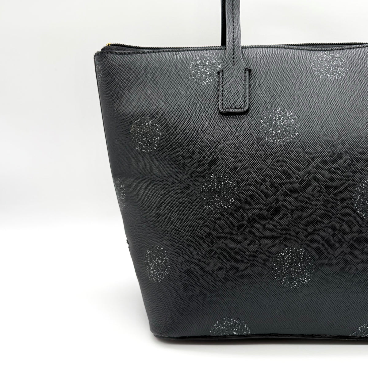 Front view of a Kate Spade black tote bag with glitter polka dots and dual handles.