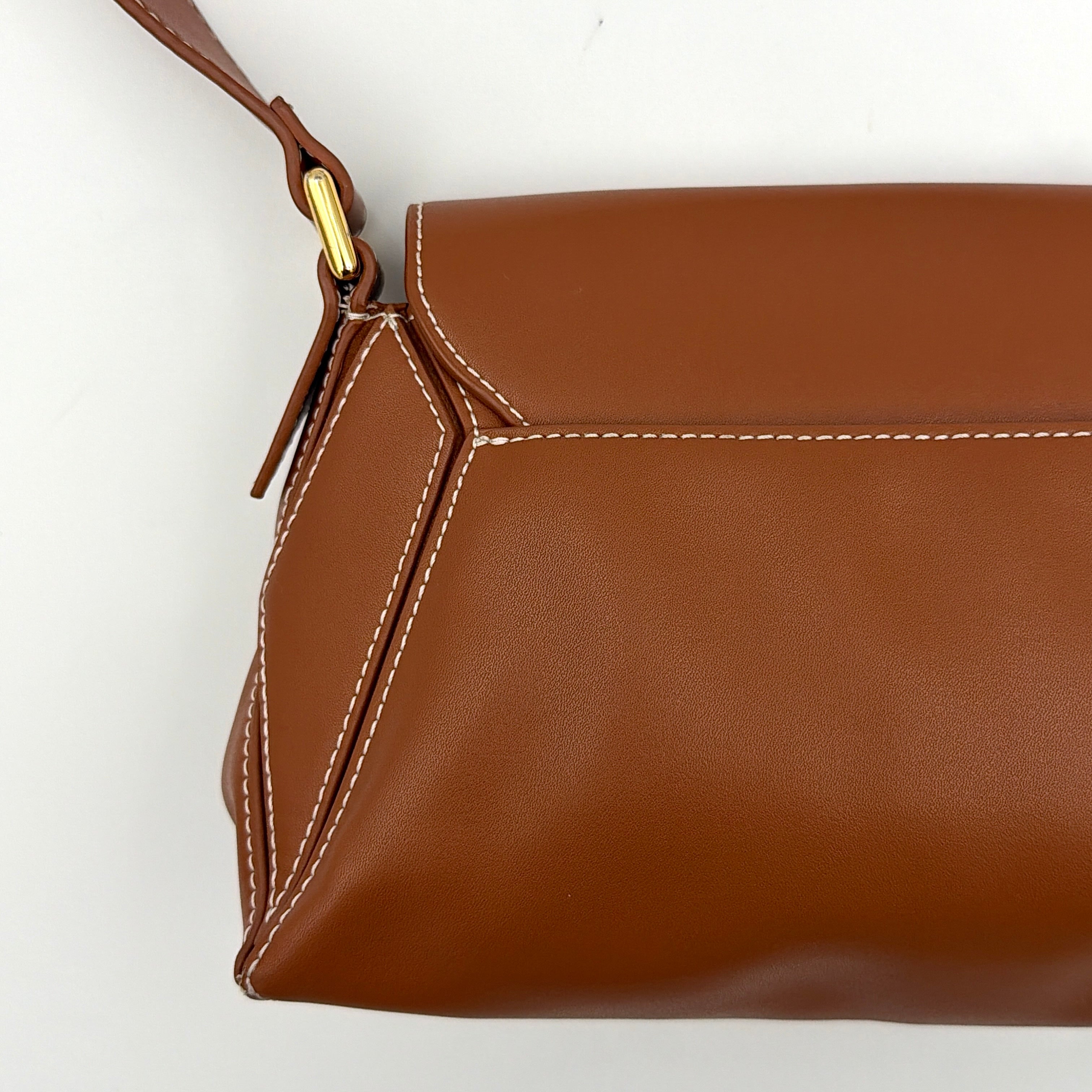Charles & Keith Nasrin Geometric Crossbody Bag in brown faux leather with angular stitching, gold-tone hardware, and adjustable strap.
