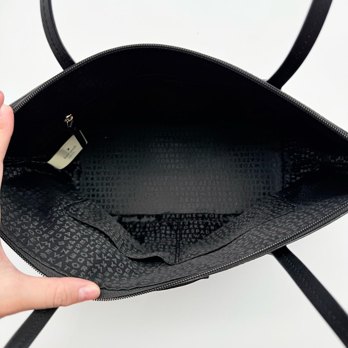 Front view of a Kate Spade black tote bag with glitter polka dots and dual handles.