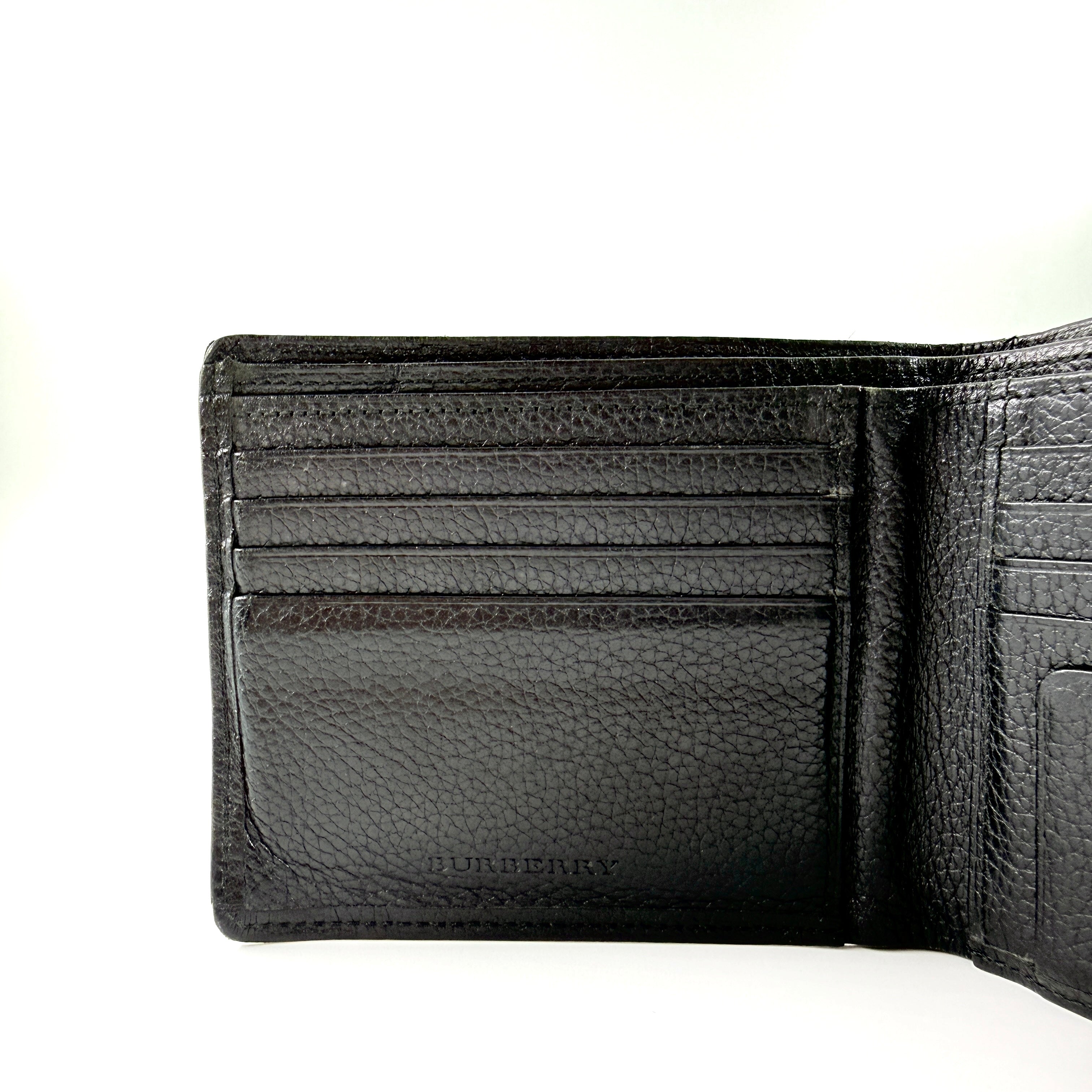 Burberry Nova Check bifold wallet in refined black grained leather with discreet embossed logo, presenting a minimal and polished silhouette.