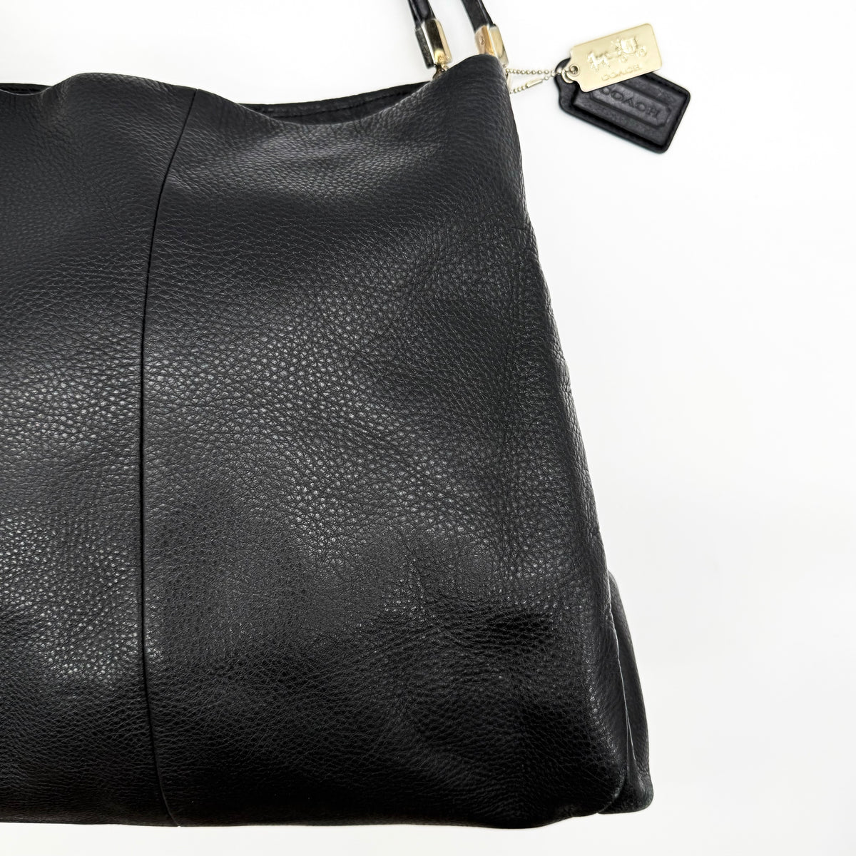 Coach Madison Phoebe Shoulder Bag in black grained leather with gold hardware and dual handles, shown against a white background.