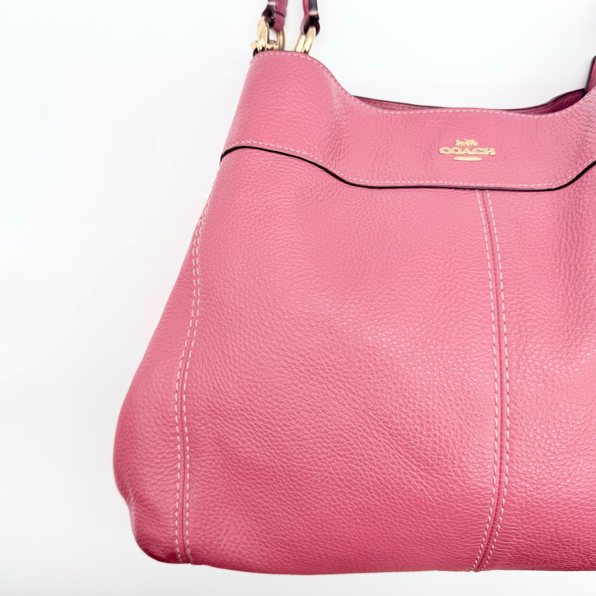 Coach Lexy Shoulder Bag in pink pebbled leather with gold hardware and dual straps, shown against a white background.