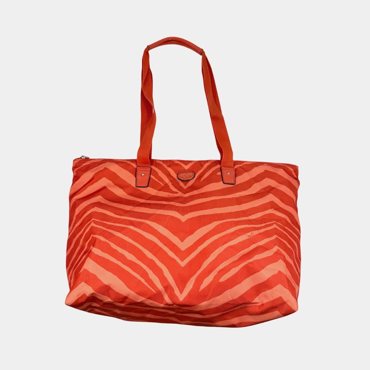 Coach Getaway Weekender tote and matching pouch in orange zebra print, with structured silhouette and bold colour.