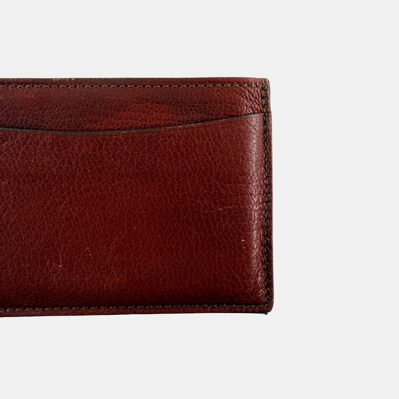Must de Cartier burgundy leather cardholder with visible natural texture and Cartier script logo, photographed against a clean background.