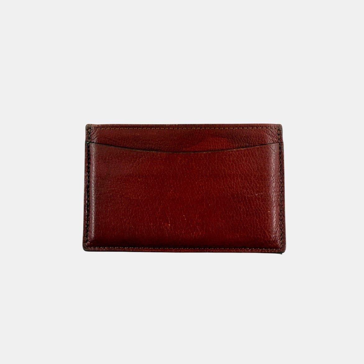 Must de Cartier burgundy leather cardholder with visible natural texture and Cartier script logo, photographed against a clean background.